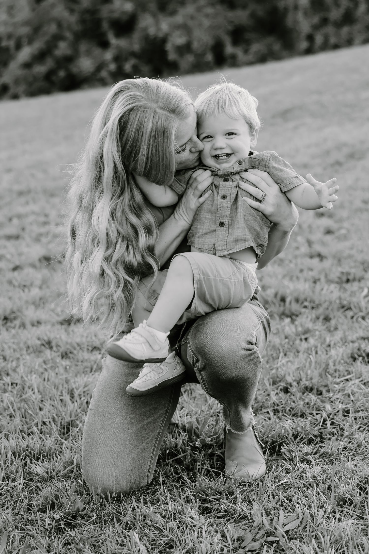 Intimate black and white portraits of family bonding moments in a grassy field.