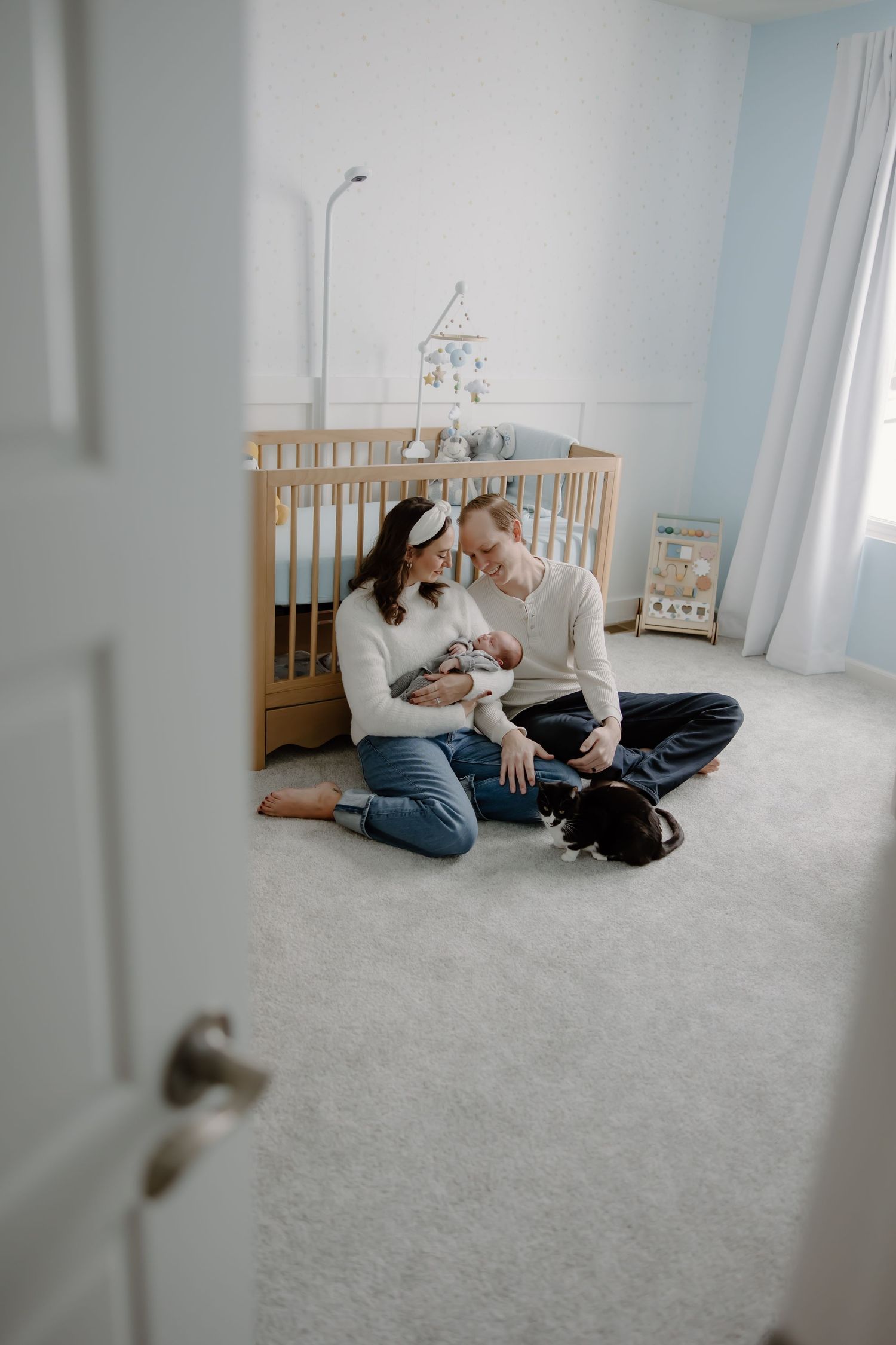 A cozy family moment on plush carpet in a bright nursery room with natural lighting.