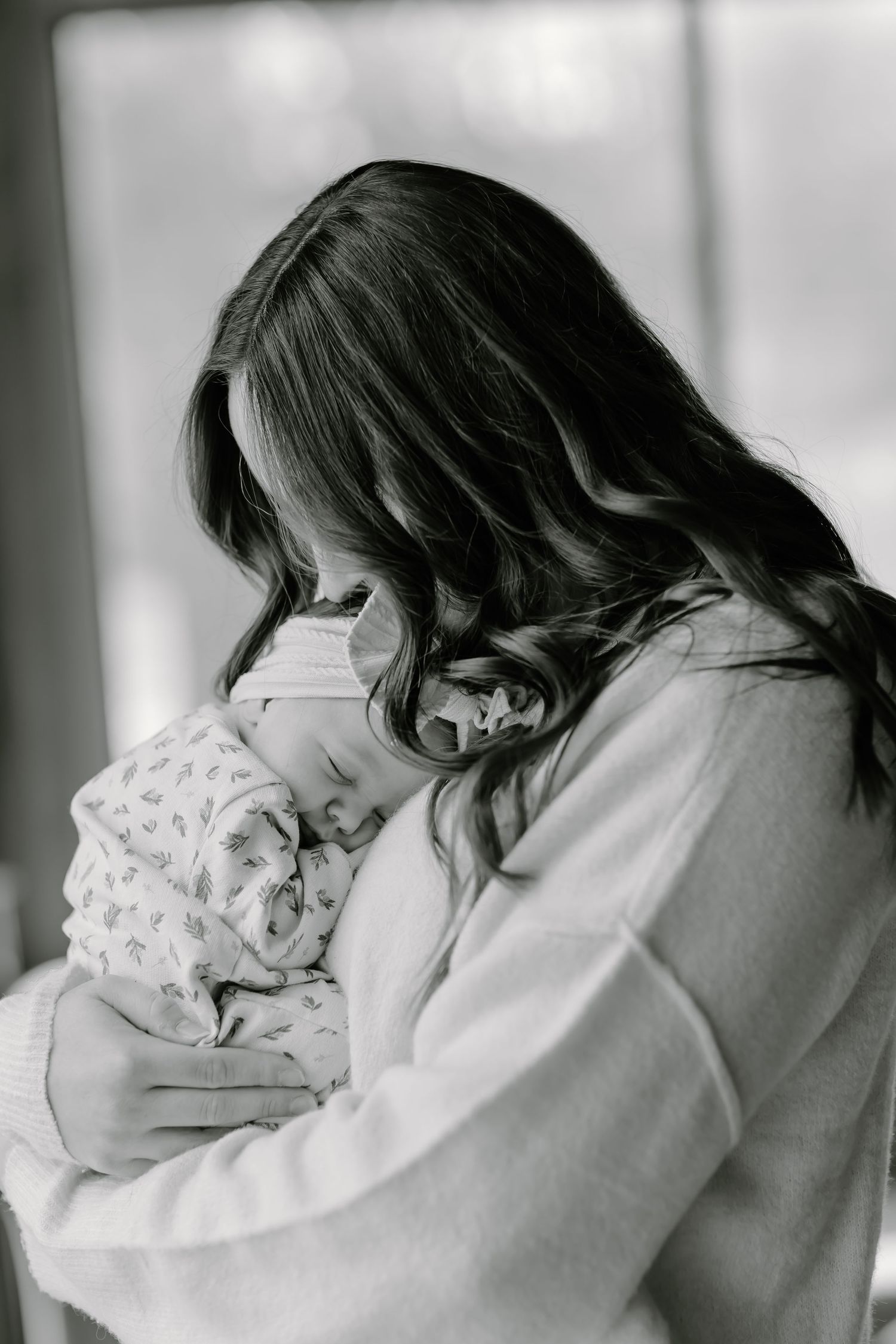 A tender black and white portrait of a parent cradling a sleeping newborn.