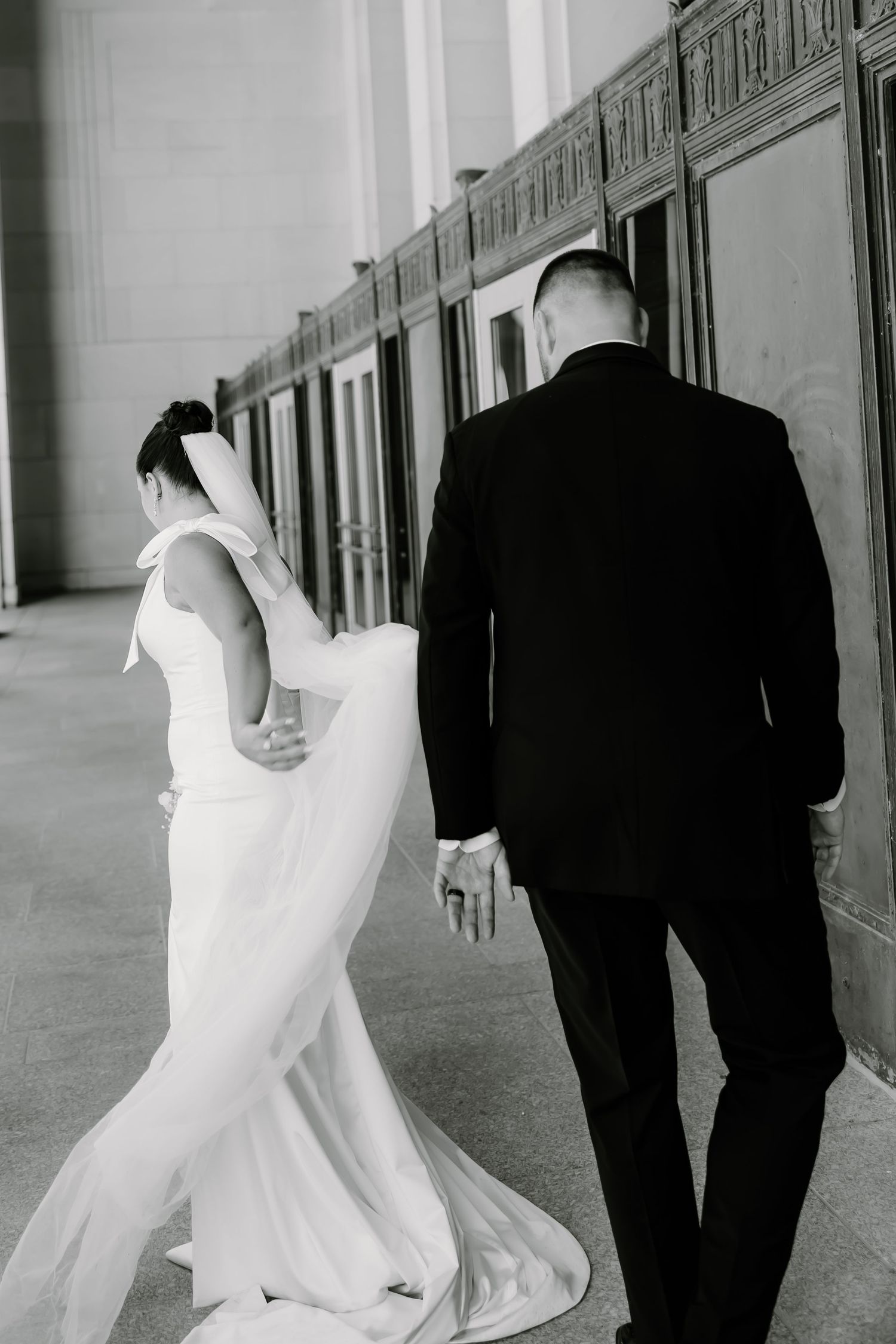 Black and white wedding photos showing movement and elegance in a hallway setting.