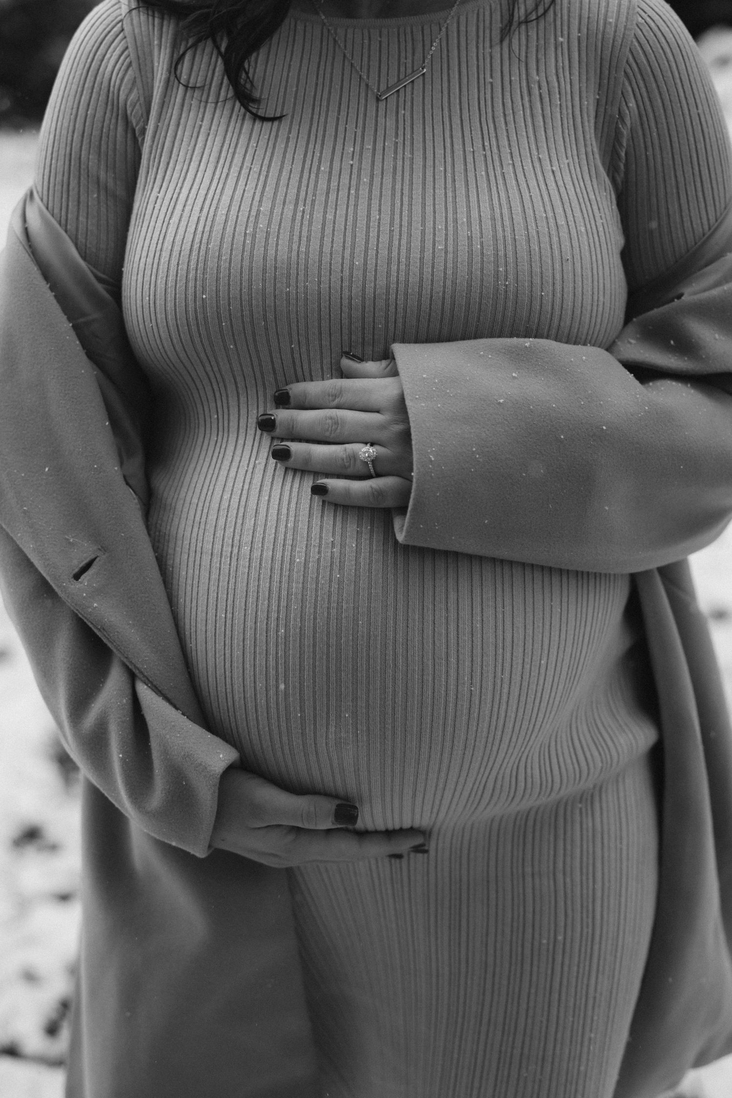Black and white maternity photos showing hands placed lovingly on pregnant belly.