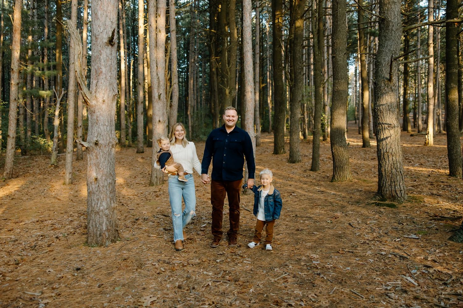 Wide angle shot of a family walking through a sunlit forest together.