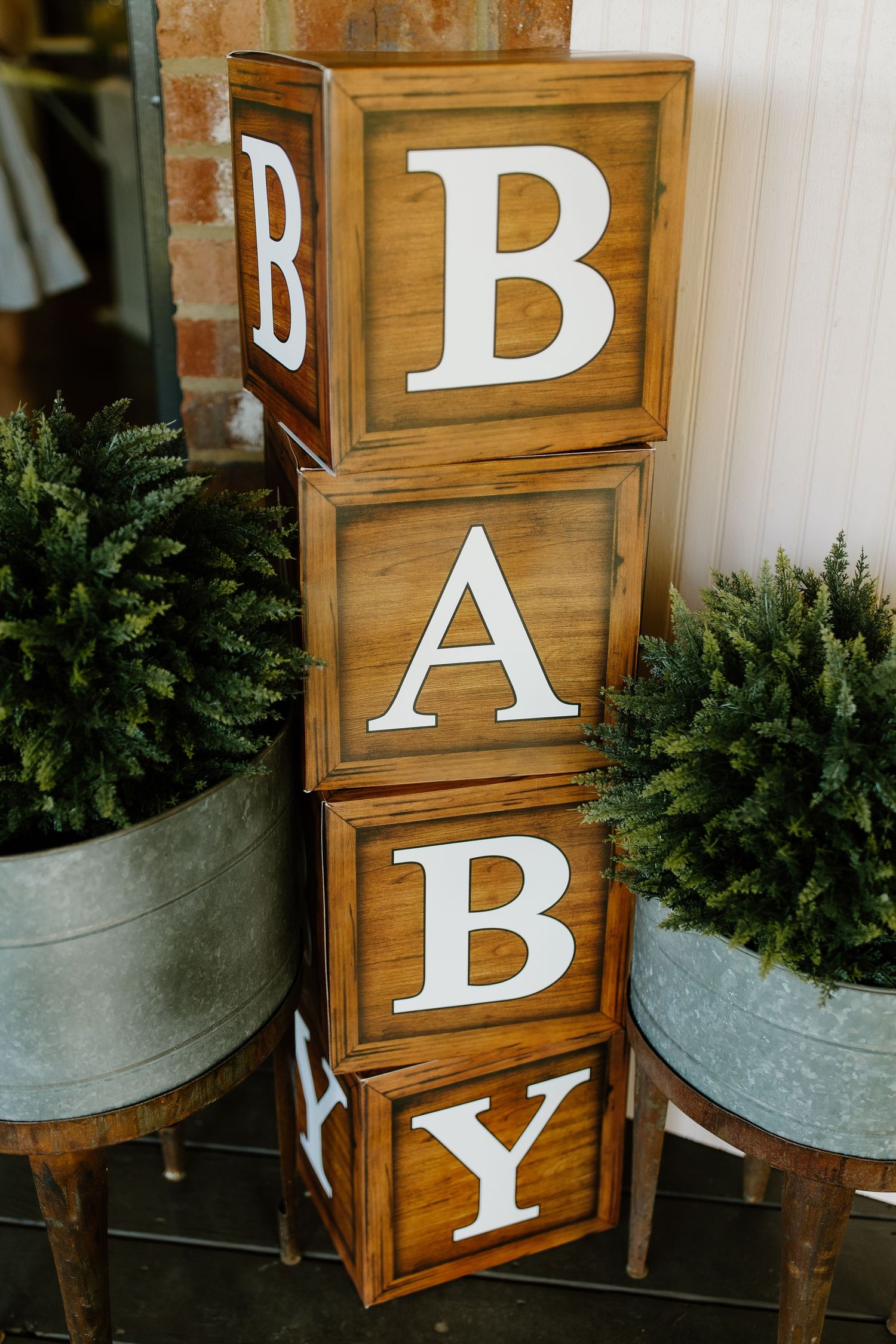 Rustic wooden signs with white letters spelling 'BAR' displayed with potted greenery in galvanized metal containers.