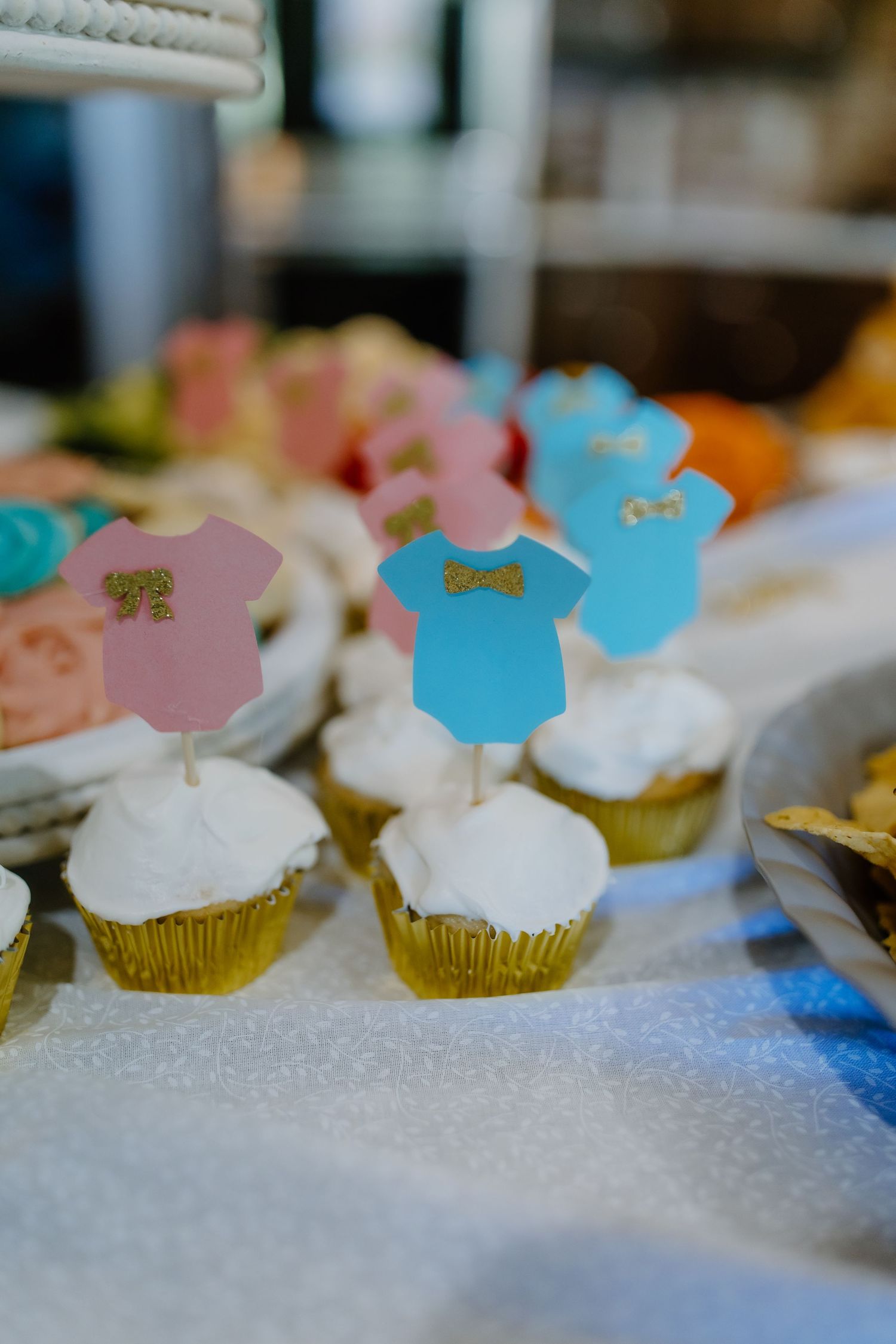 Cupcakes decorated with pink and blue toppers arranged on a white surface.