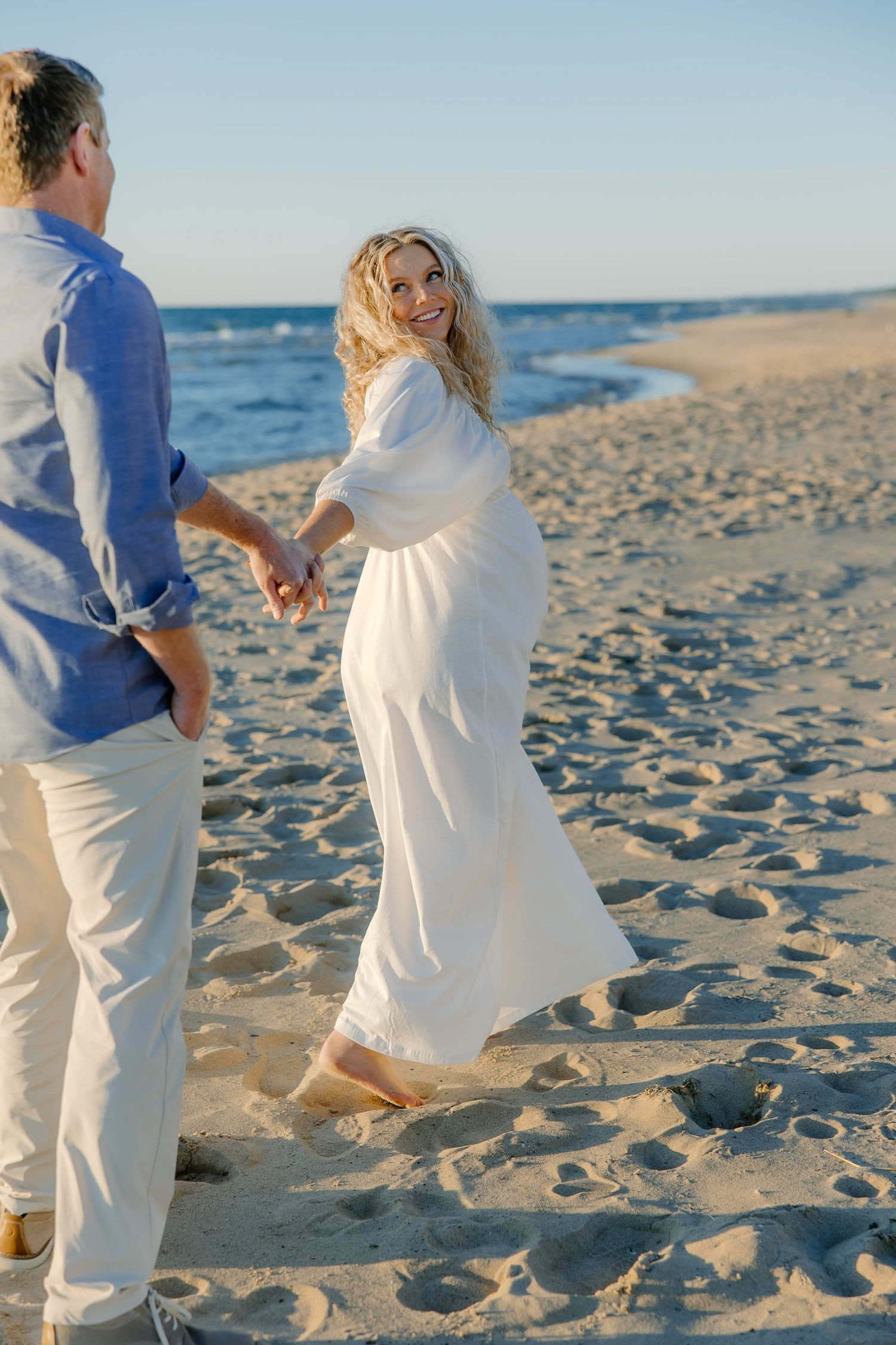 People in white and blue attire walking together on a sunny beach.