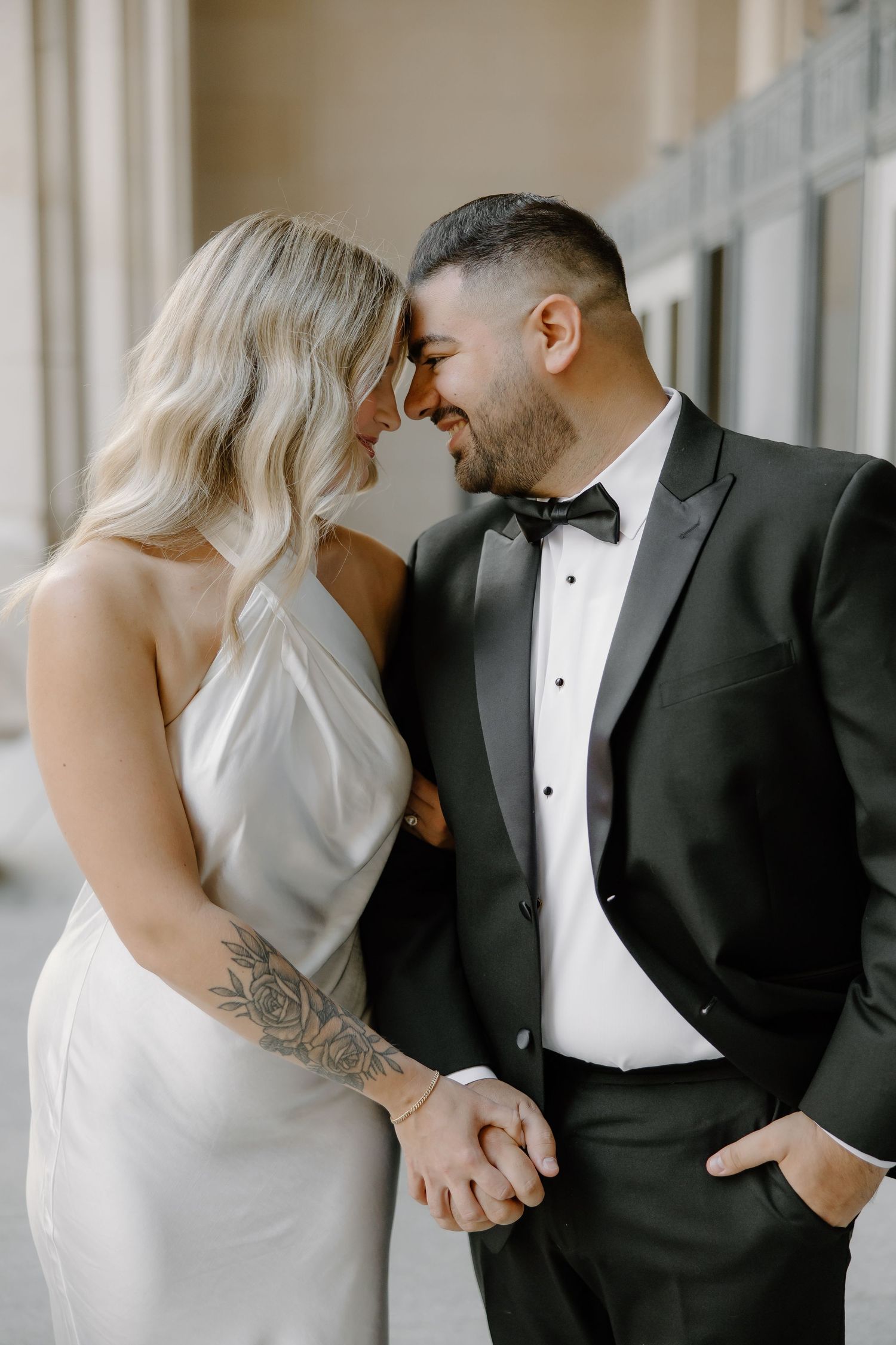 Intimate moment between couple in formal attire against bright window.