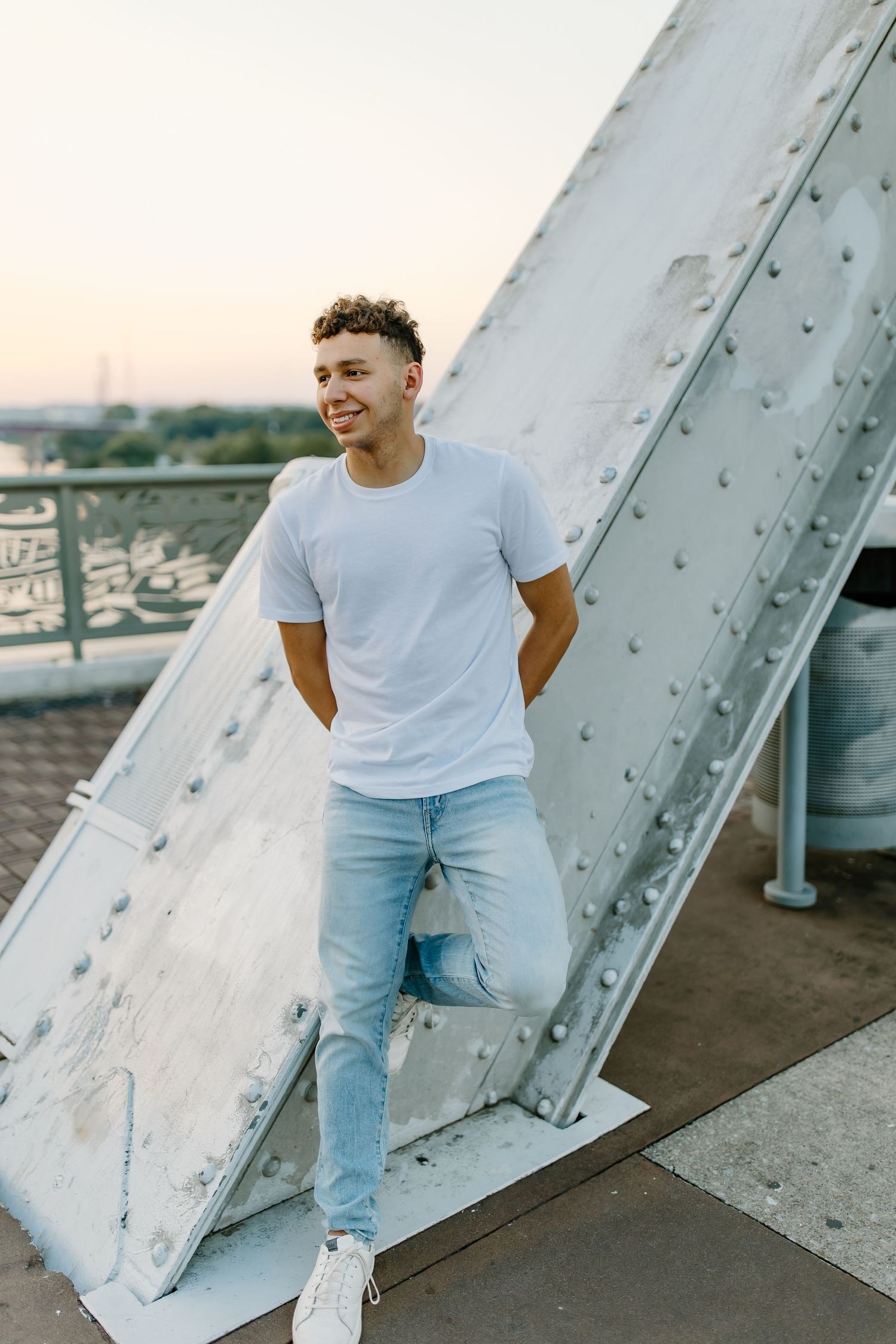 Casual fashion portrait against white metal structure in natural lighting.