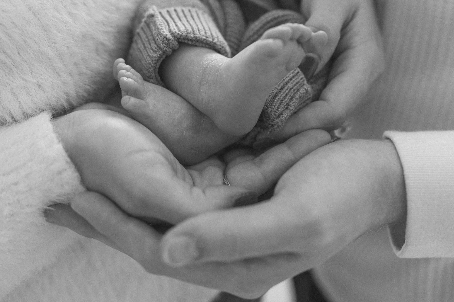 Newborn baby details with tiny hands and feet in soft black and white.
