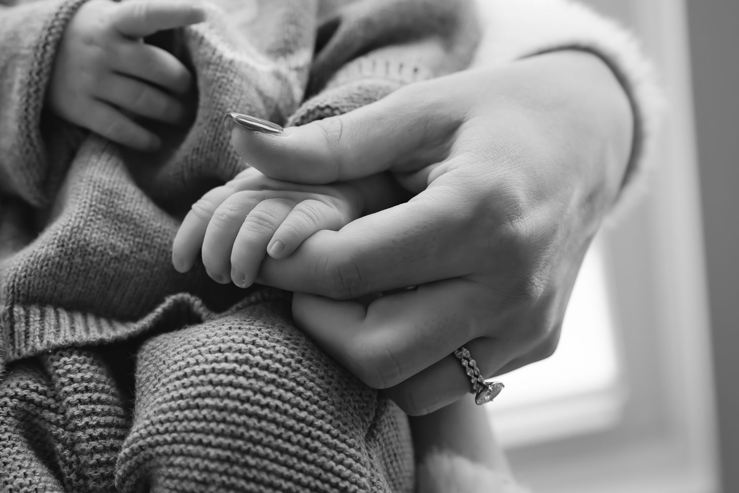 Black and white close-up of gentle hands cradling a newborn.
