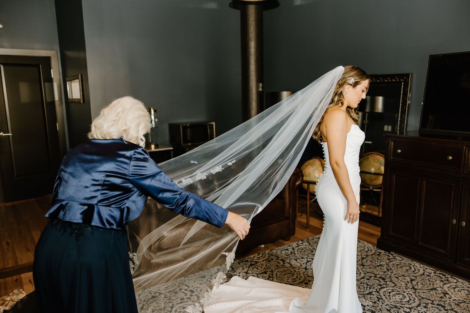 A flowing white wedding veil is adjusted in an intimate indoor setting.