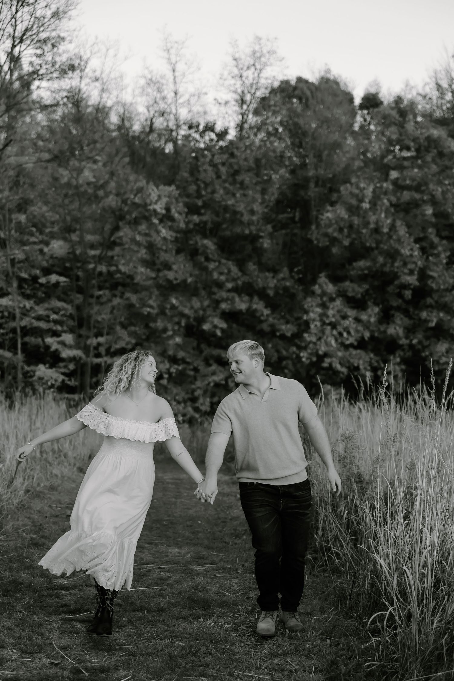 A romantic couple dances in a field surrounded by autumn trees and tall grass.