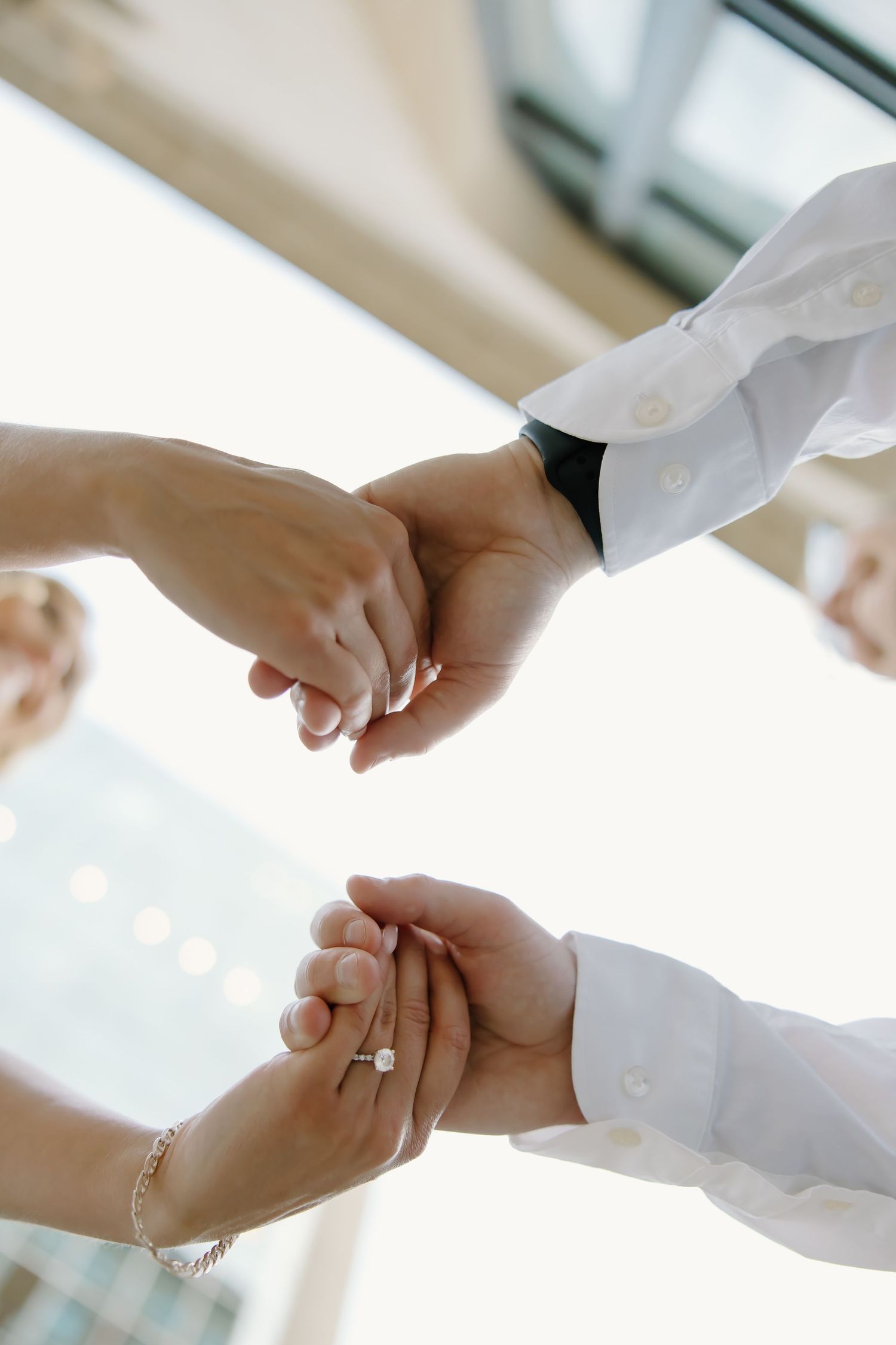 Close-up of hands holding during wedding ceremony with engagement ring visible.