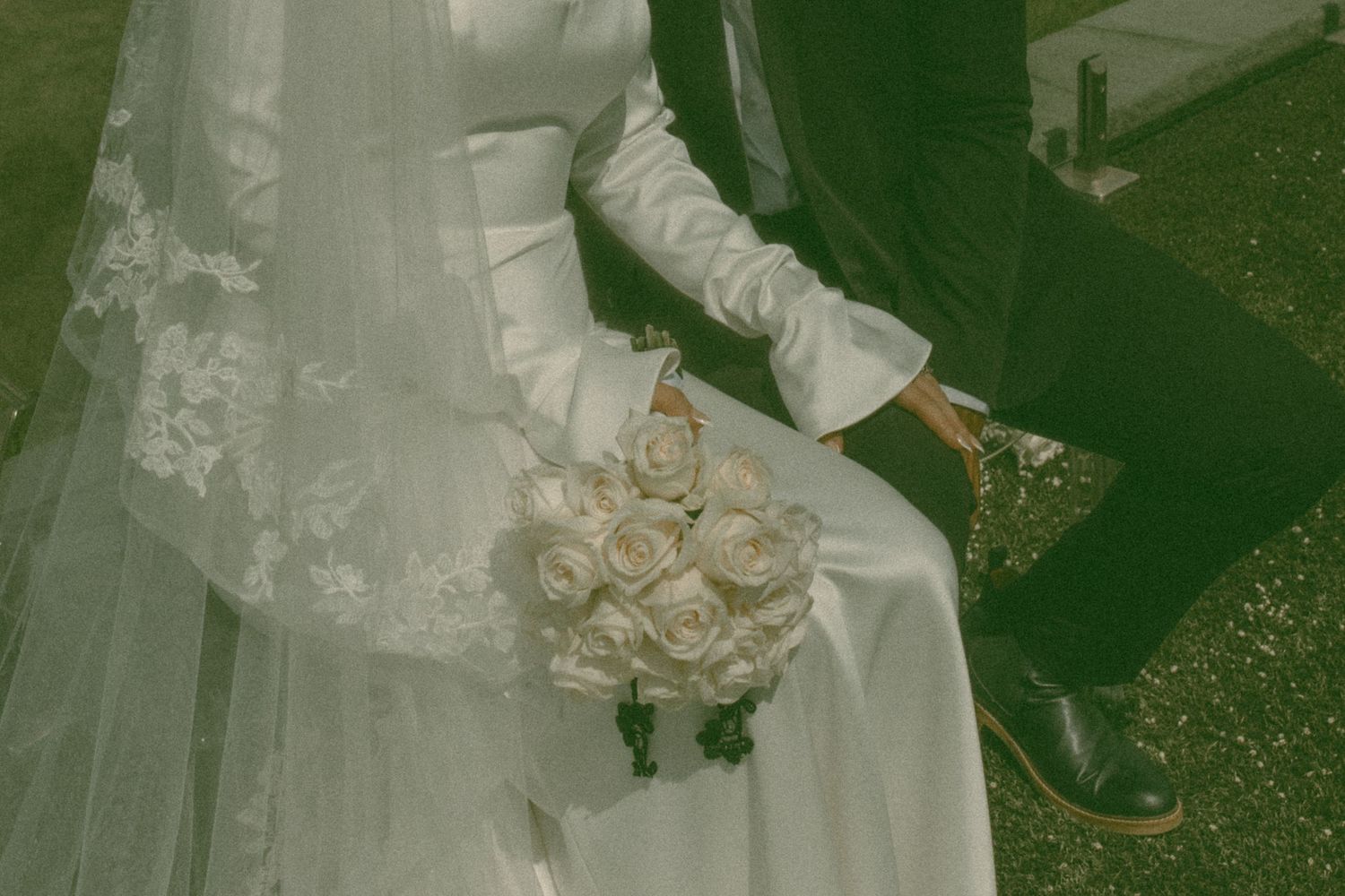 A bride in a white dress holds a bouquet in a garden setting with natural greenery.