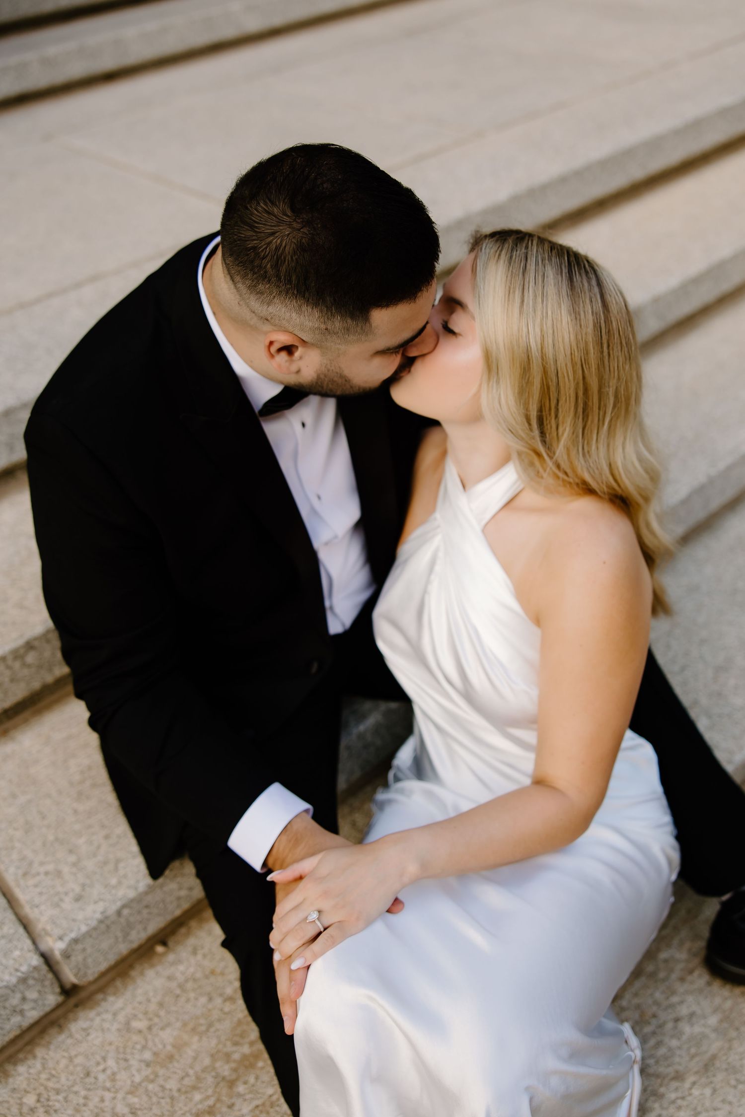 Intimate wedding couple shares tender moments on concrete steps.