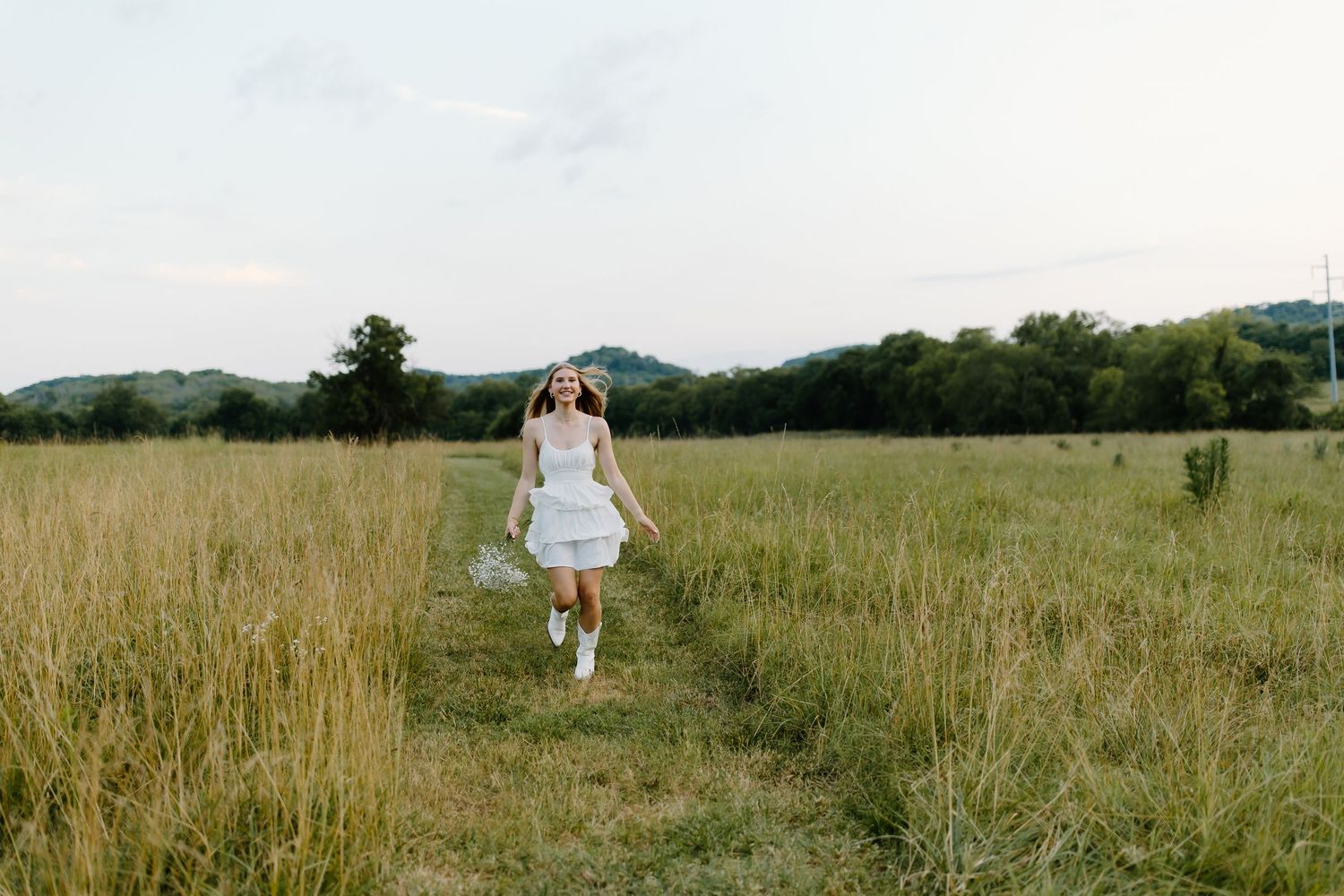 Figure walking through a serene meadow landscape with mountains in the distance.