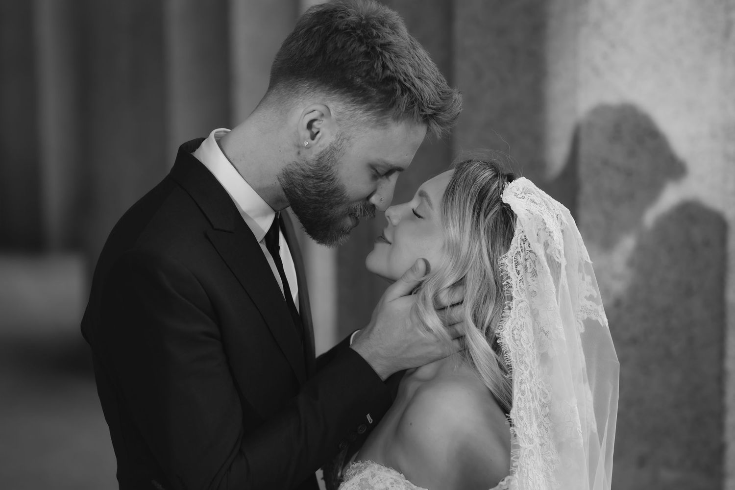 Black and white wedding photo of bride and groom sharing a tender kiss, bride wearing veil.