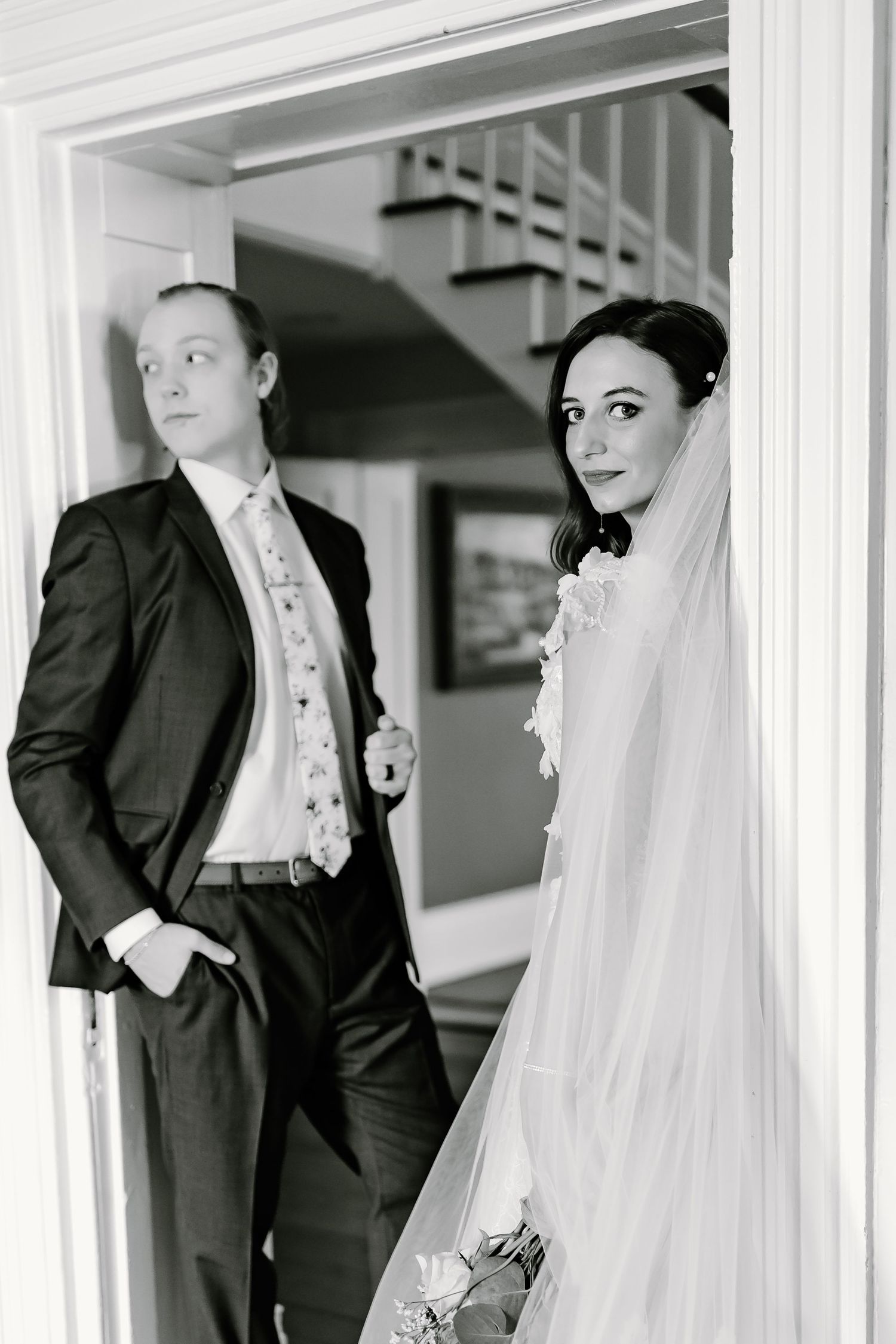Wedding couple poses in classic black and white portraits along a bright white hallway.