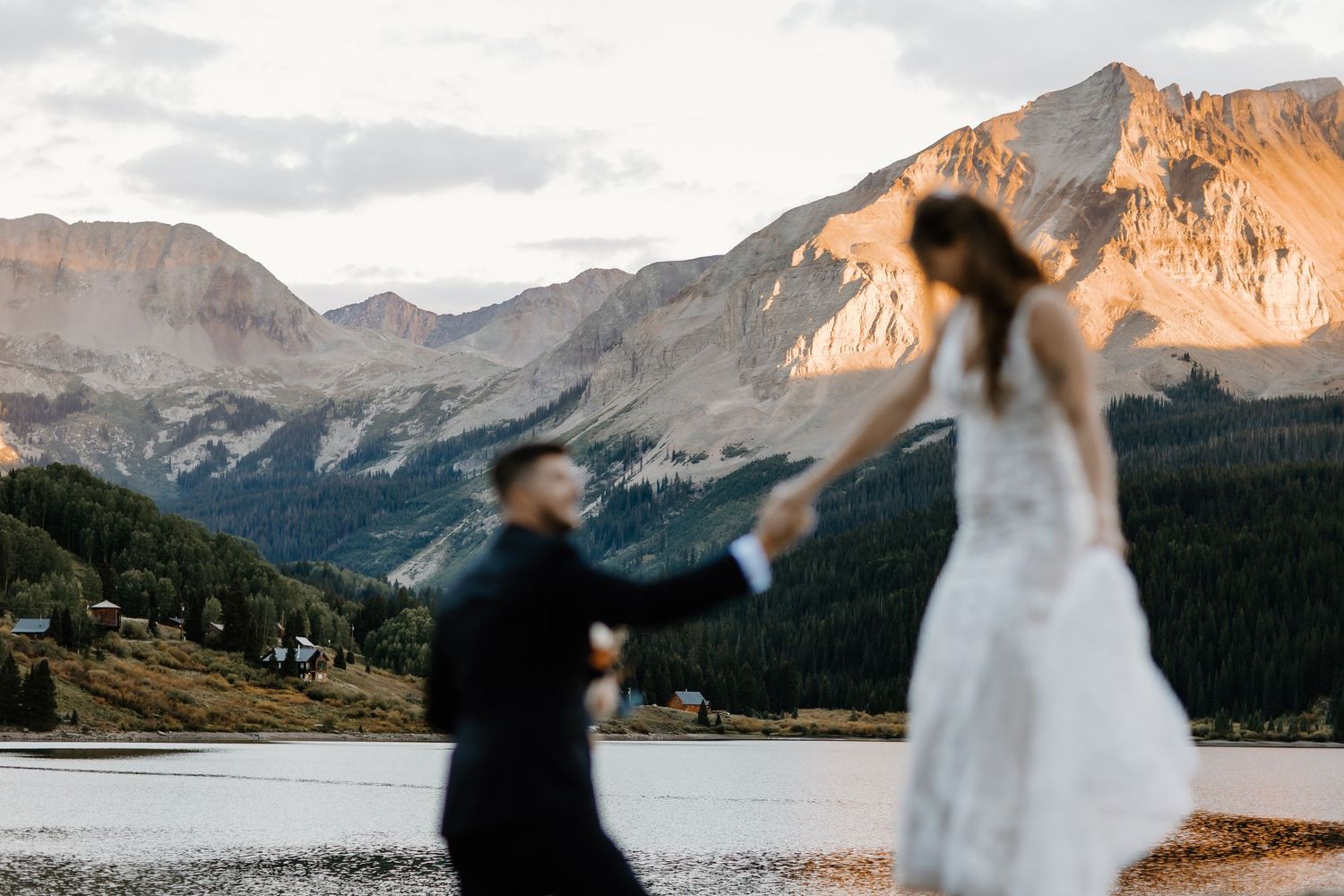 Artistic motion blur wedding photo with mountain peaks glowing in golden light.