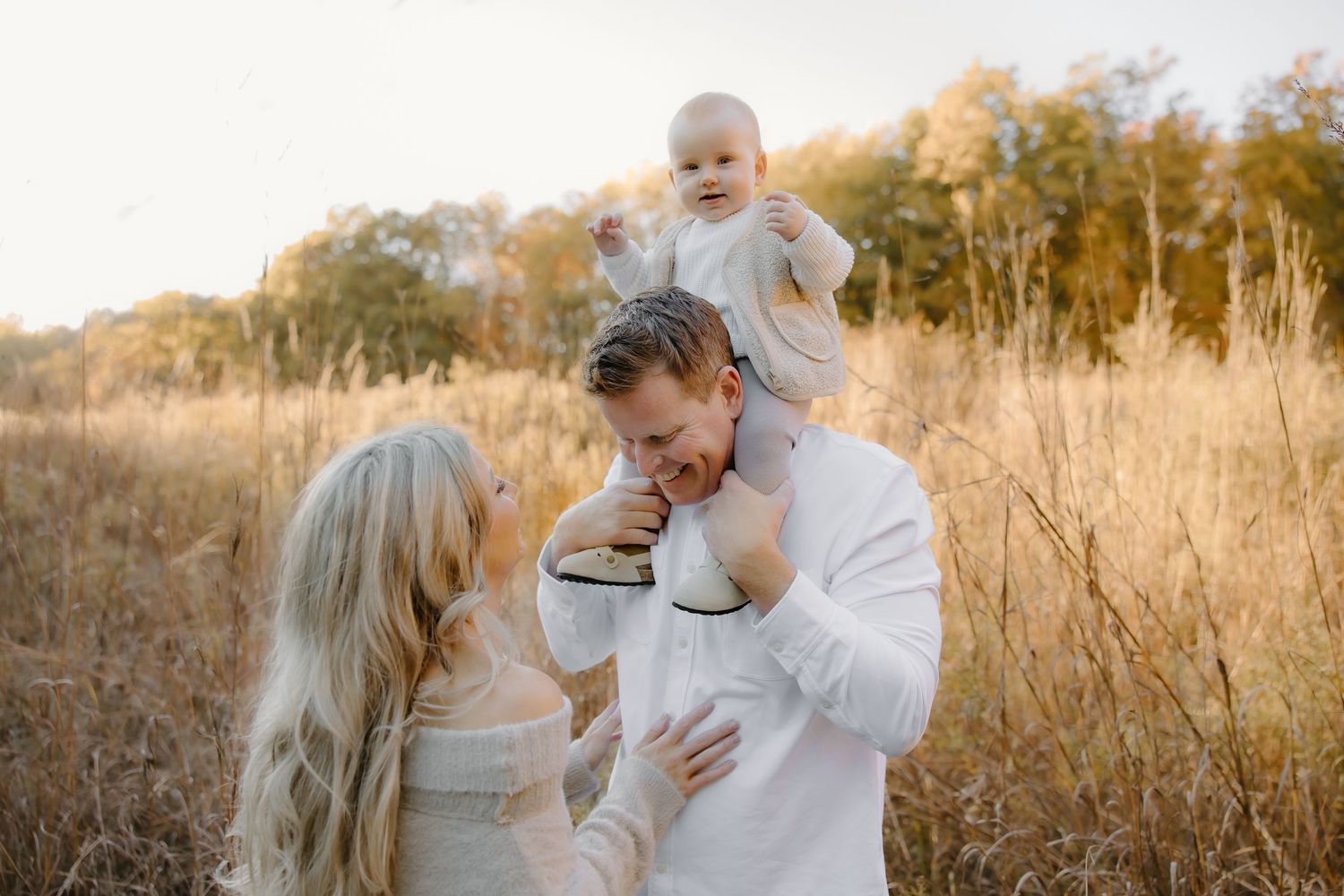 A family shares a tender moment together in a golden autumn field at sunset.