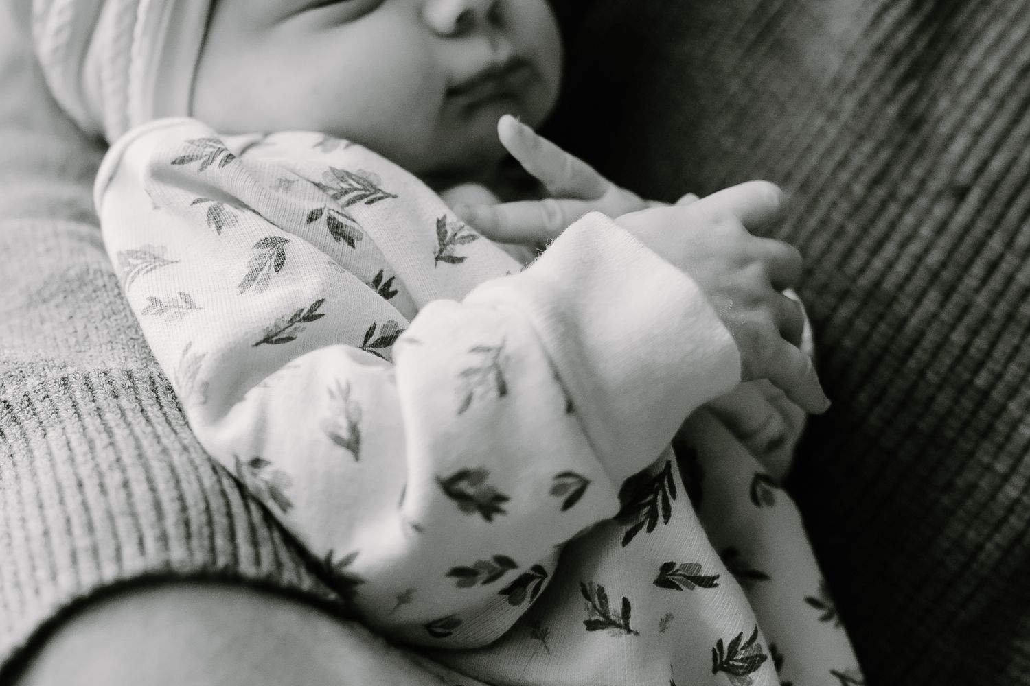 Sweet details of a sleeping newborn in a patterned onesie.