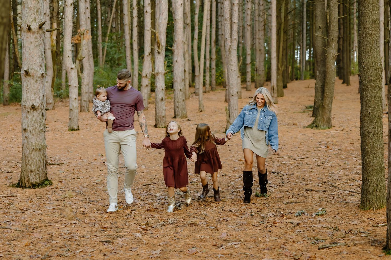 Family walking together among tall pine trees in an autumn forest.