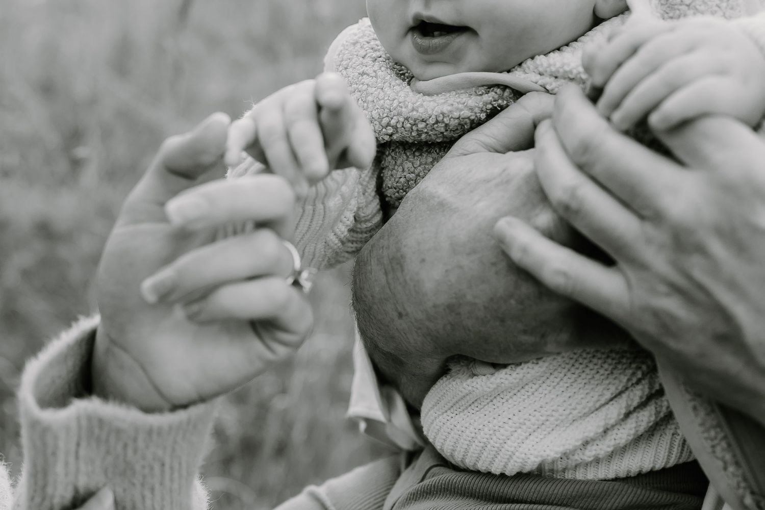 Close-up black and white image of small hands touching a textured surface.