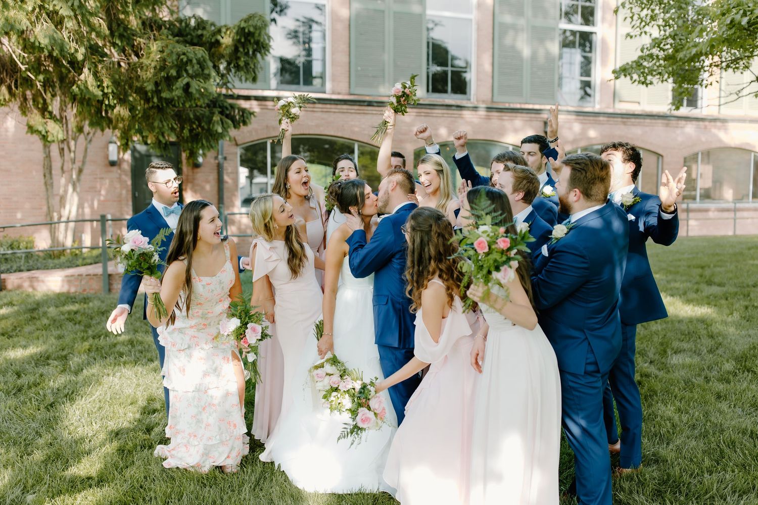 Wedding party in navy blue and white dresses standing on green lawn.