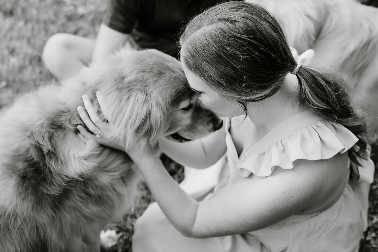 Intimate family moment with their pet dog on grass in black and white.