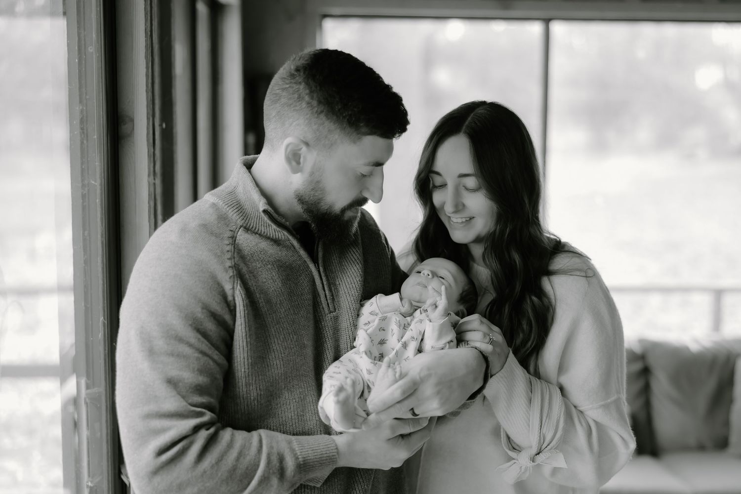 Family gathering by a bright window sharing special moments with their newborn.