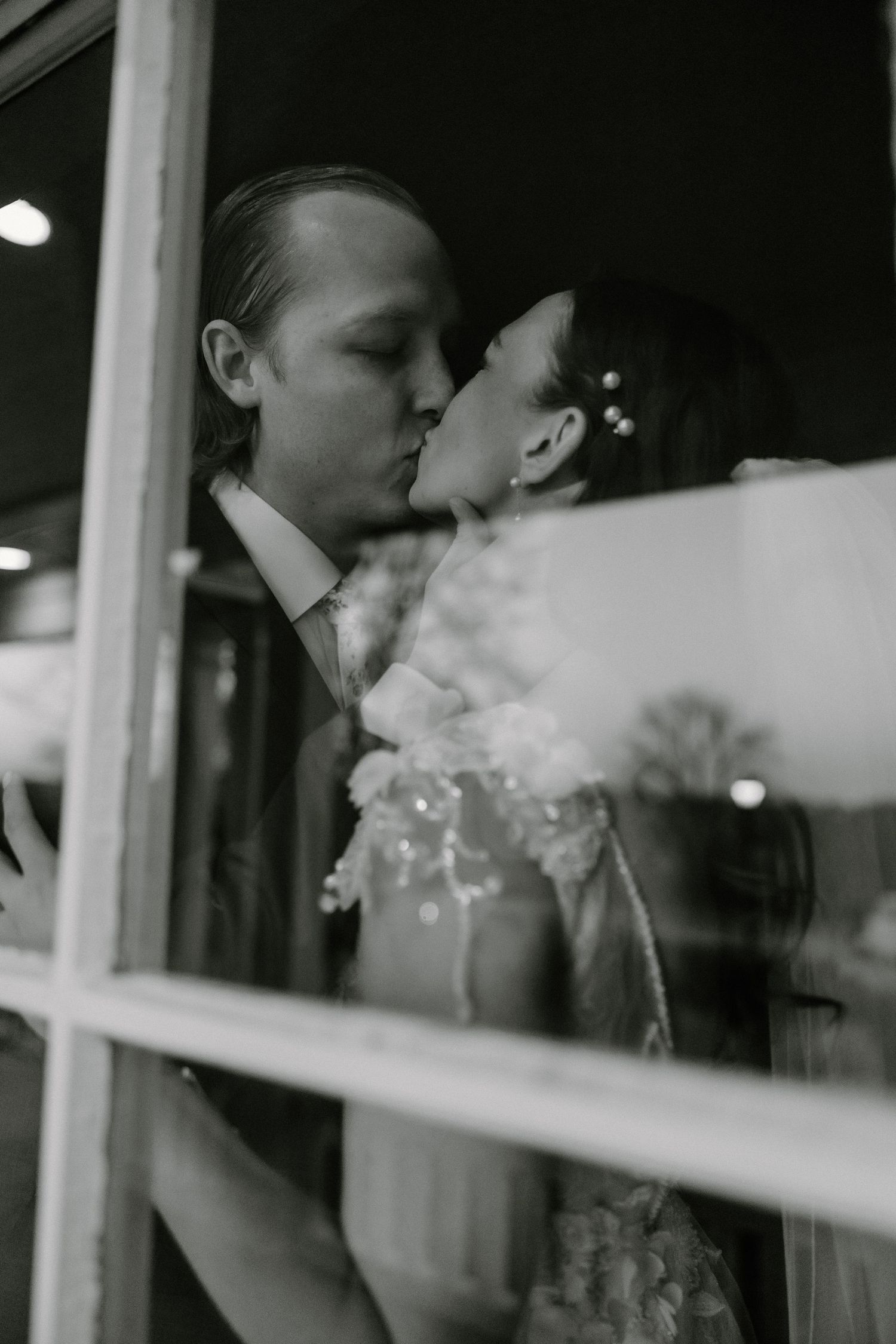Moody black and white window portraits showing intimate wedding reflections.