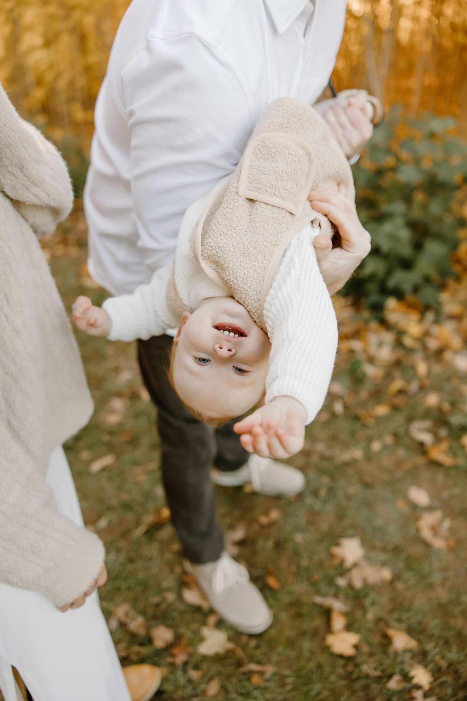 Playful moments captured on grass with autumn leaves in background.