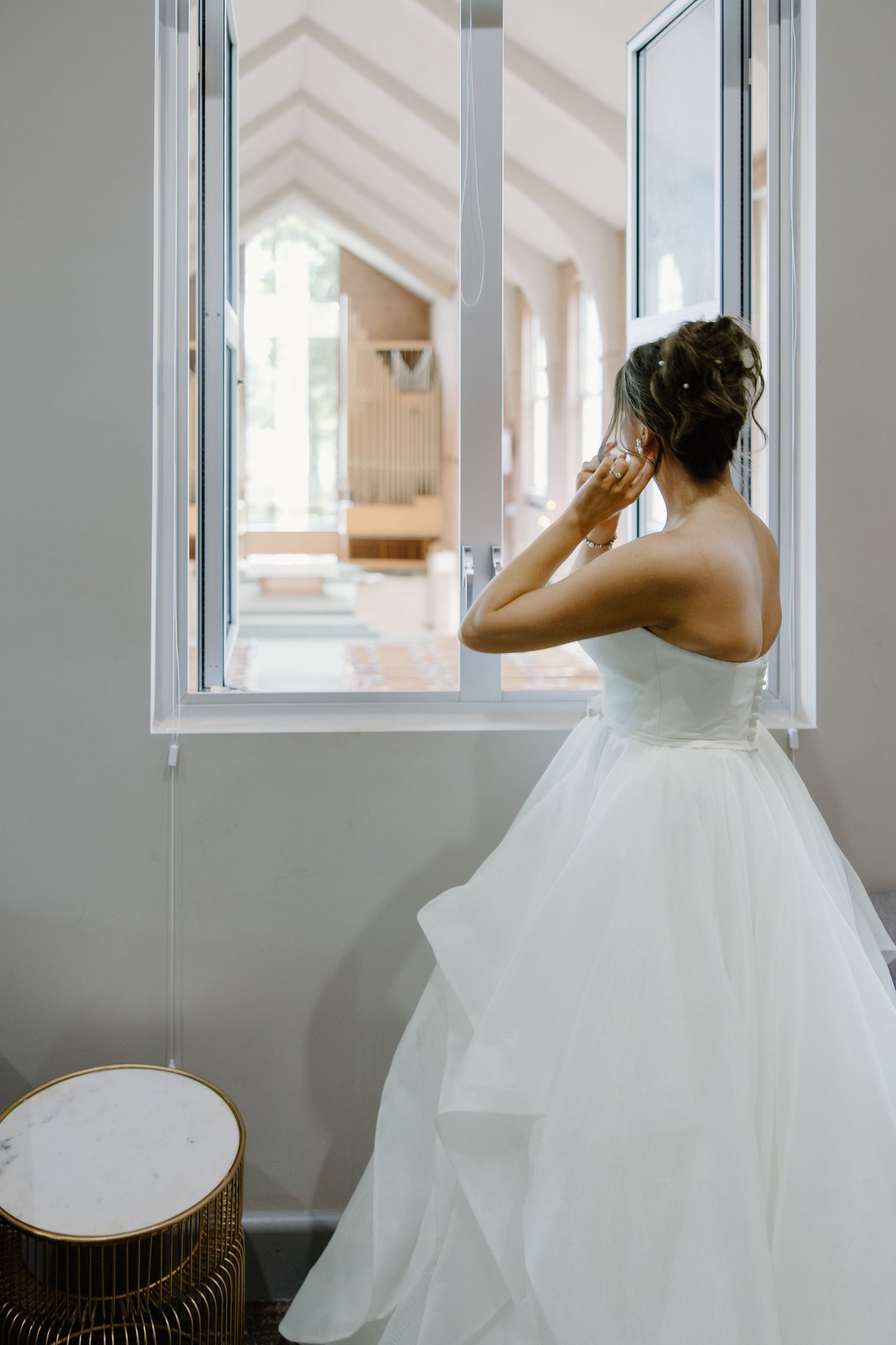 White tulle ballgown wedding dress photographed near bright window.