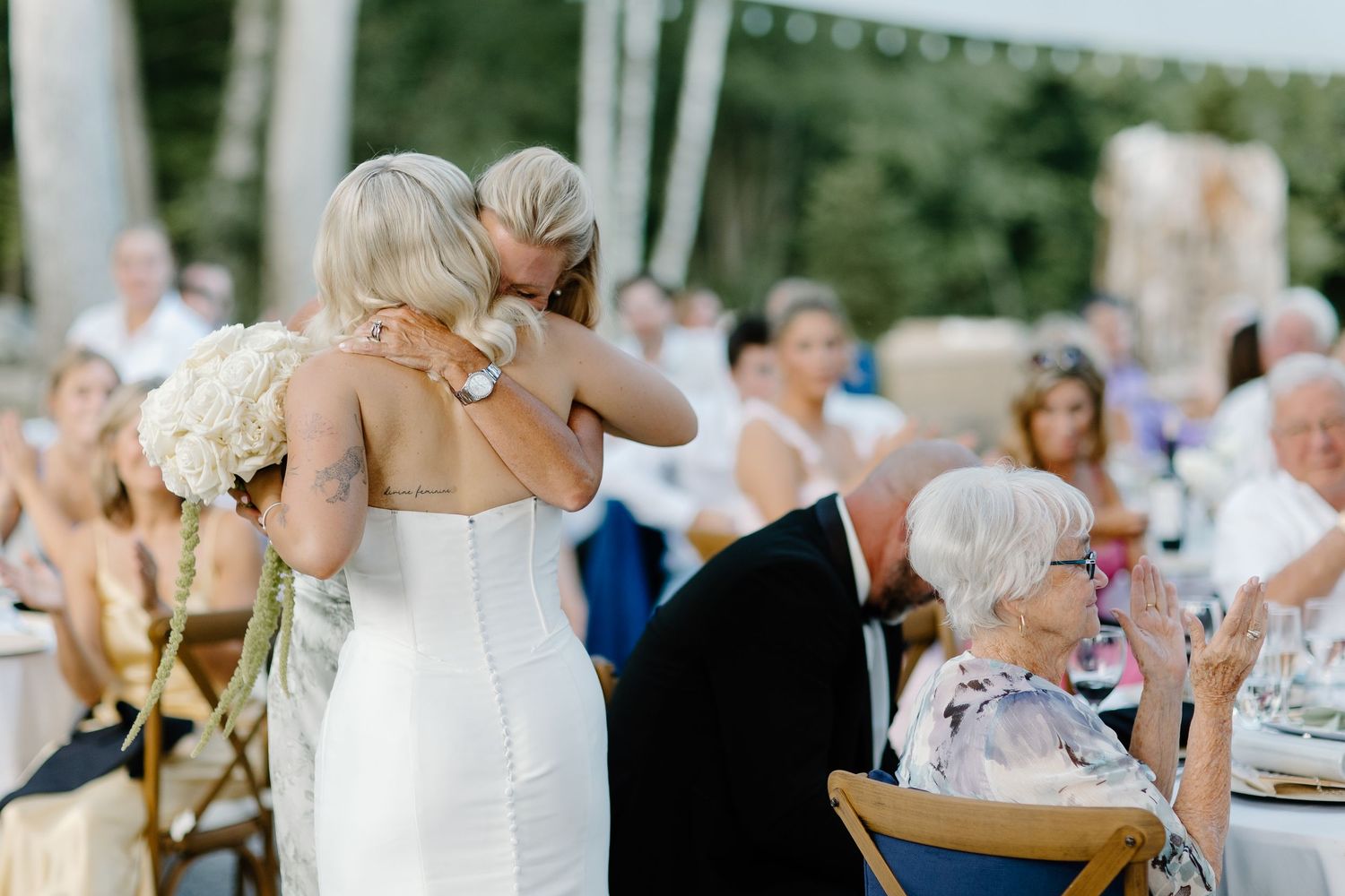 Wedding celebration at outdoor venue with guests seated at decorated tables.