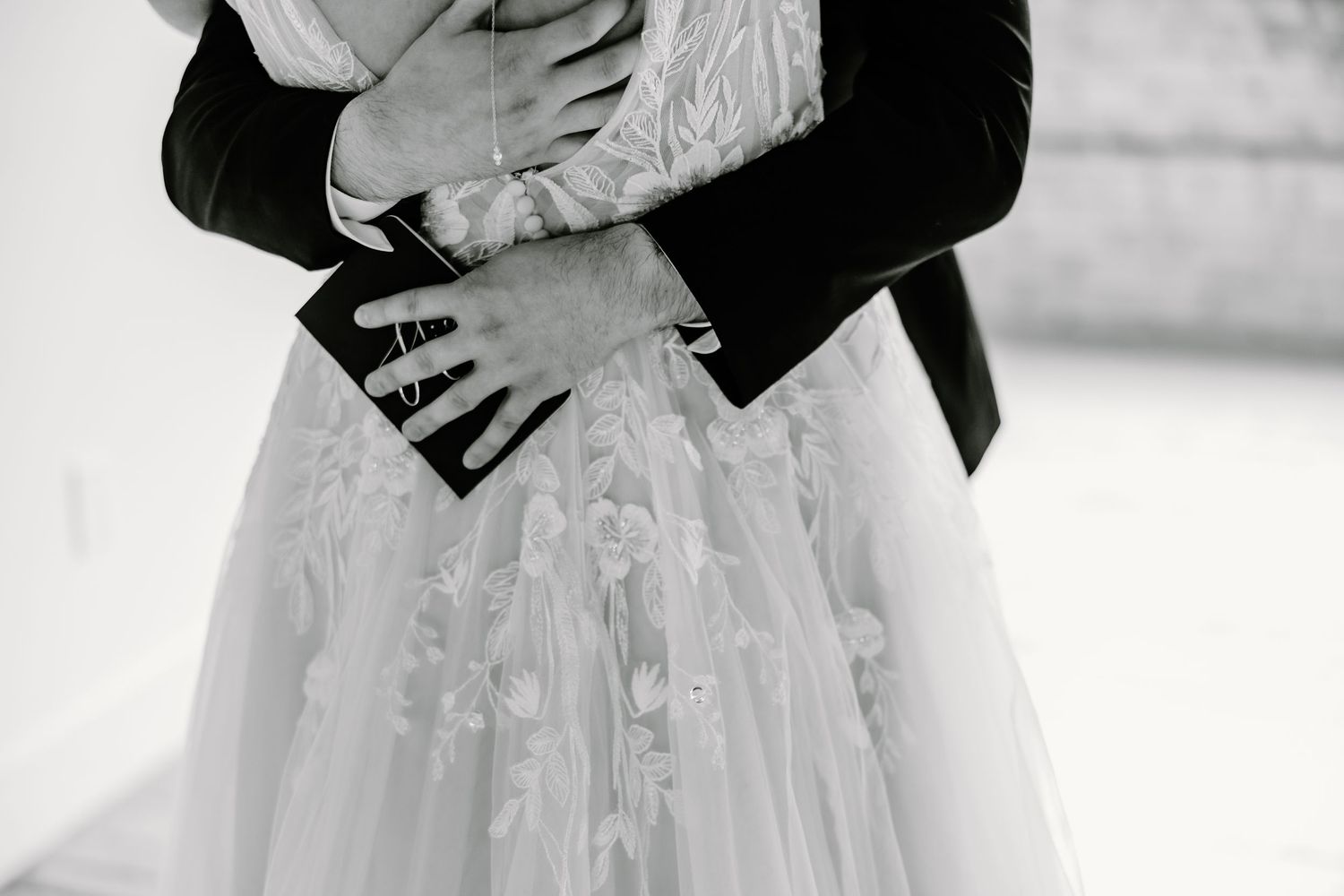 Close-up details of a white lace wedding dress with delicate embroidery patterns.