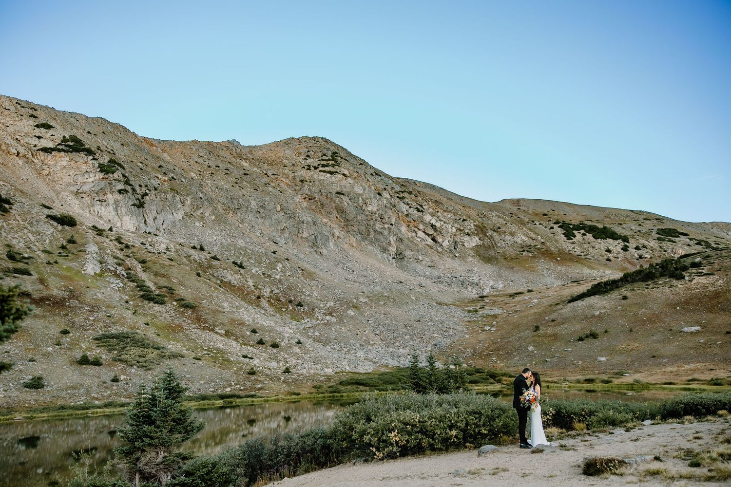 Panoramic mountain vista with clear blue skies and rocky terrain.
