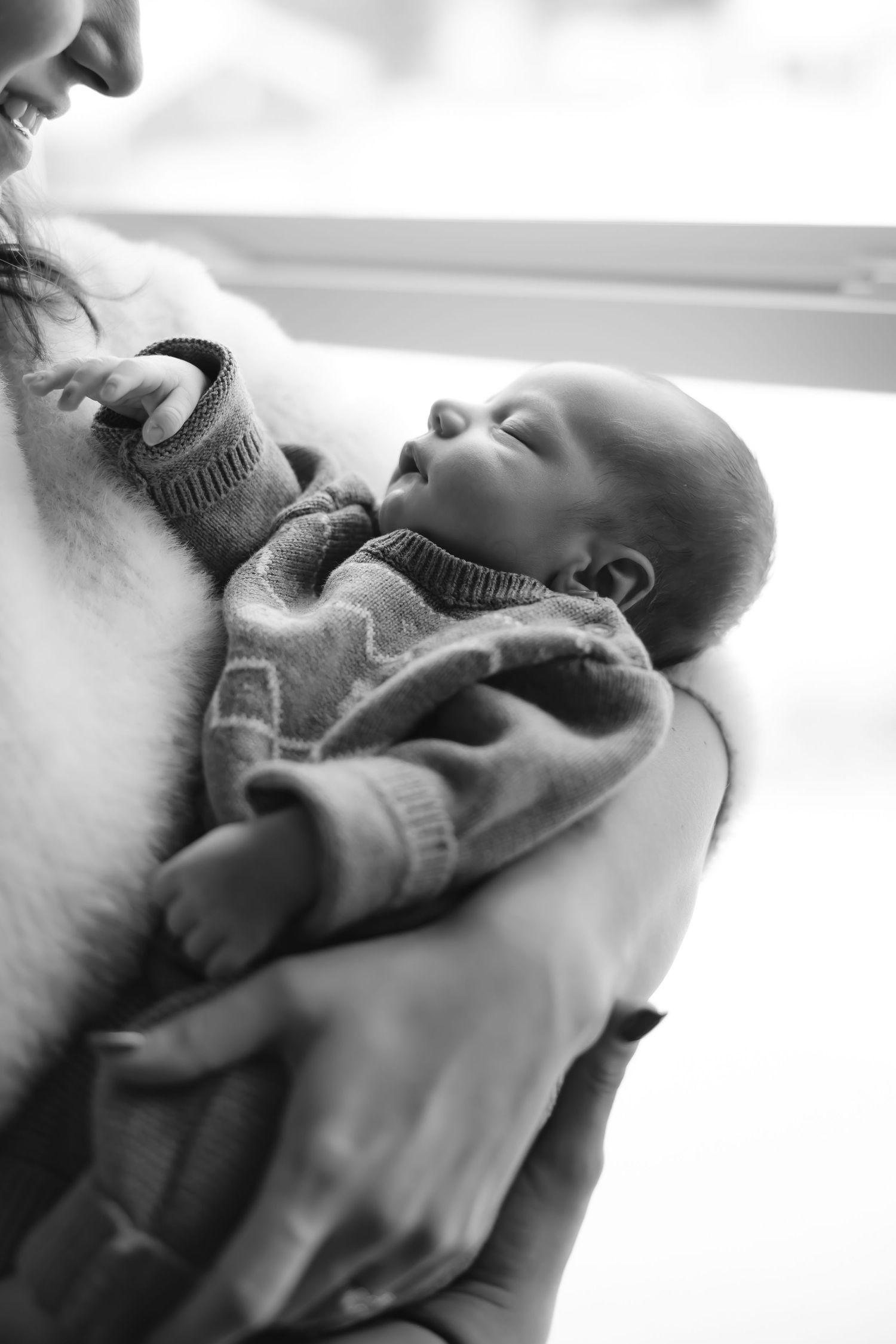 Black and white close-up shots of a sleeping newborn swaddled in soft fabric.
