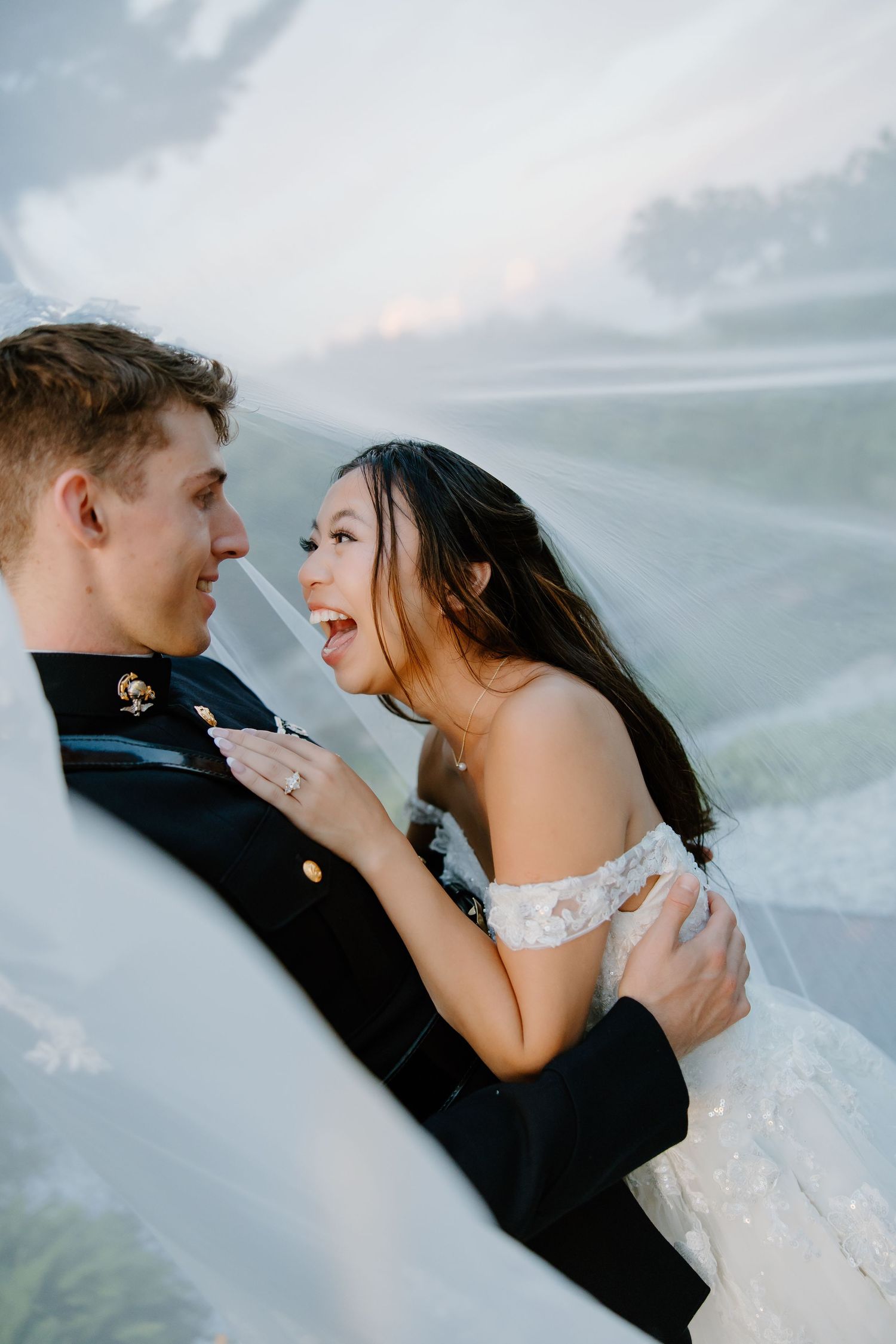 Romantic wedding couple poses against cloudy sky in dramatic lighting.