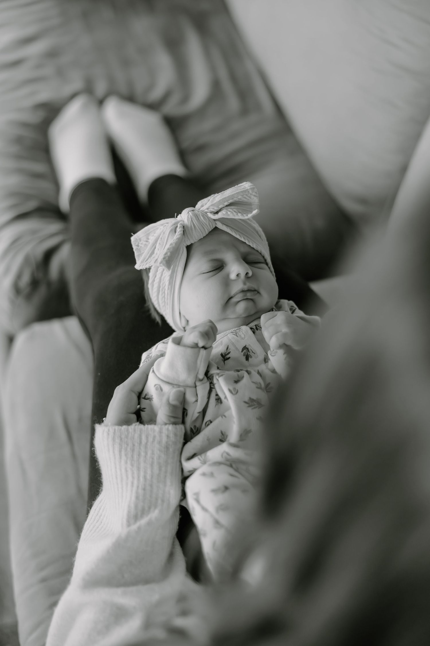 Tender black and white portrait of a sleeping newborn in soft lighting.