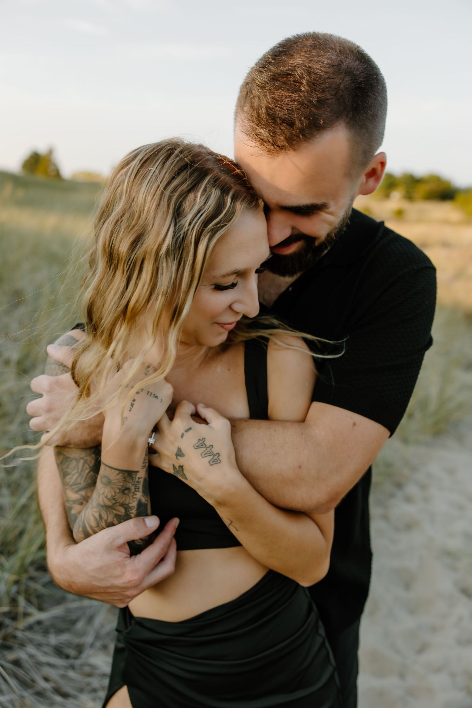 An intimate embrace in a field of tall grass during golden hour.