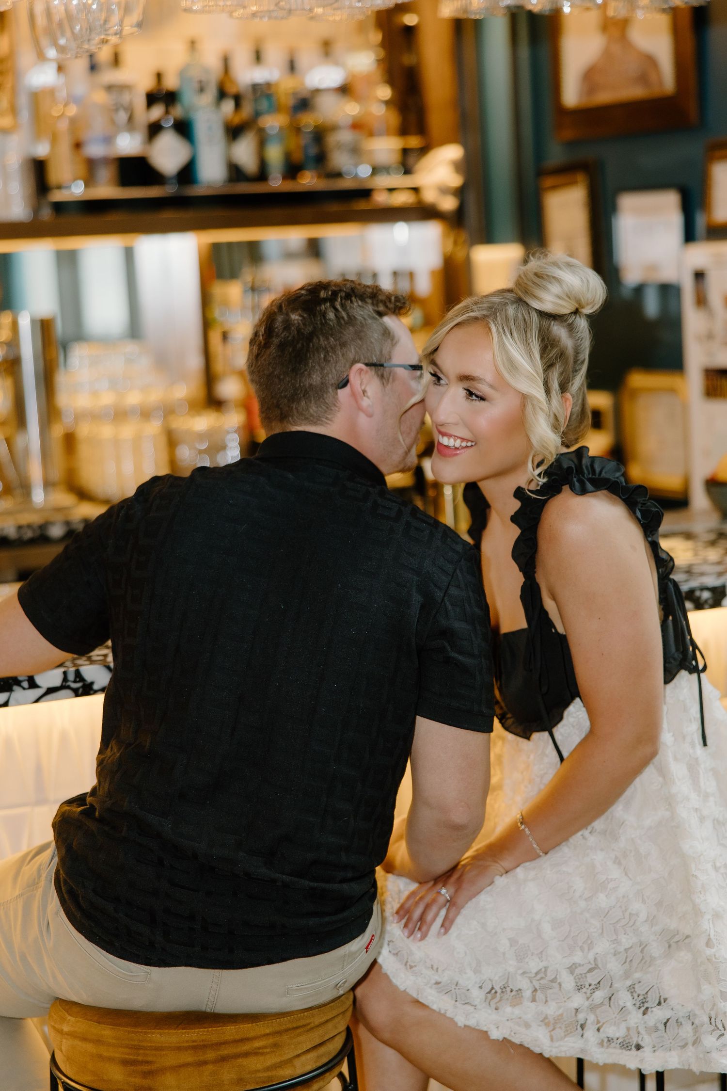 Couple enjoying drinks together at an elegant bar with crystal chandeliers.