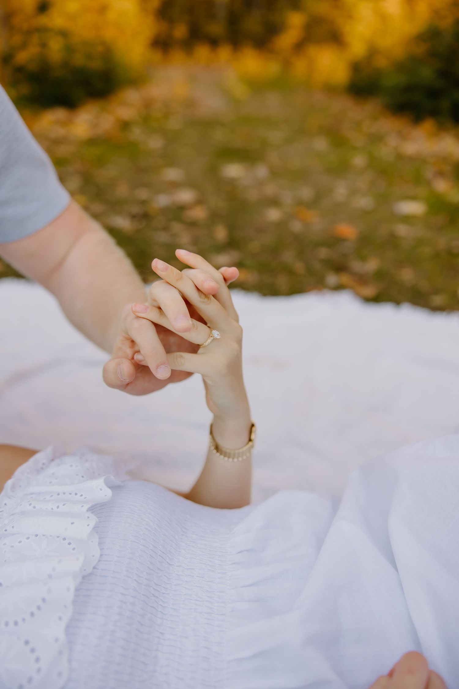 Detail shot of hands with white lace dress fabric in golden autumn light.