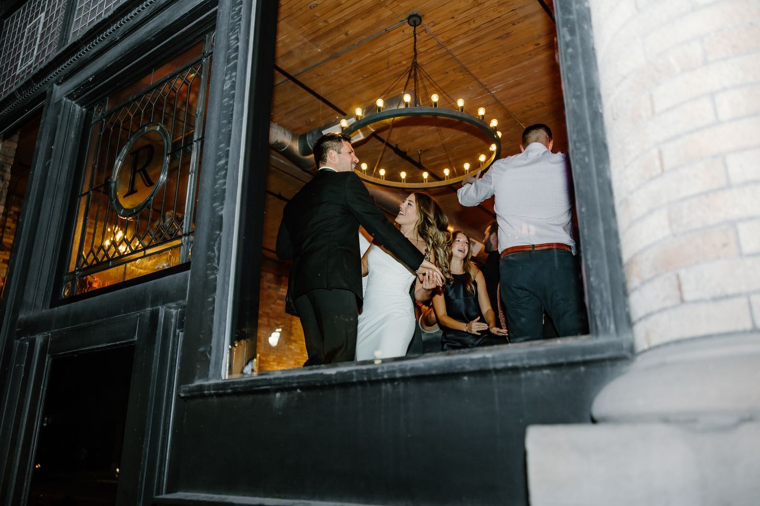 Wedding reception dance sequence with string lights and brick walls.