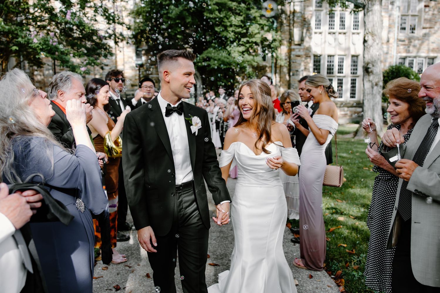 Wedding party celebrating outdoors on a beautiful day near stone buildings.