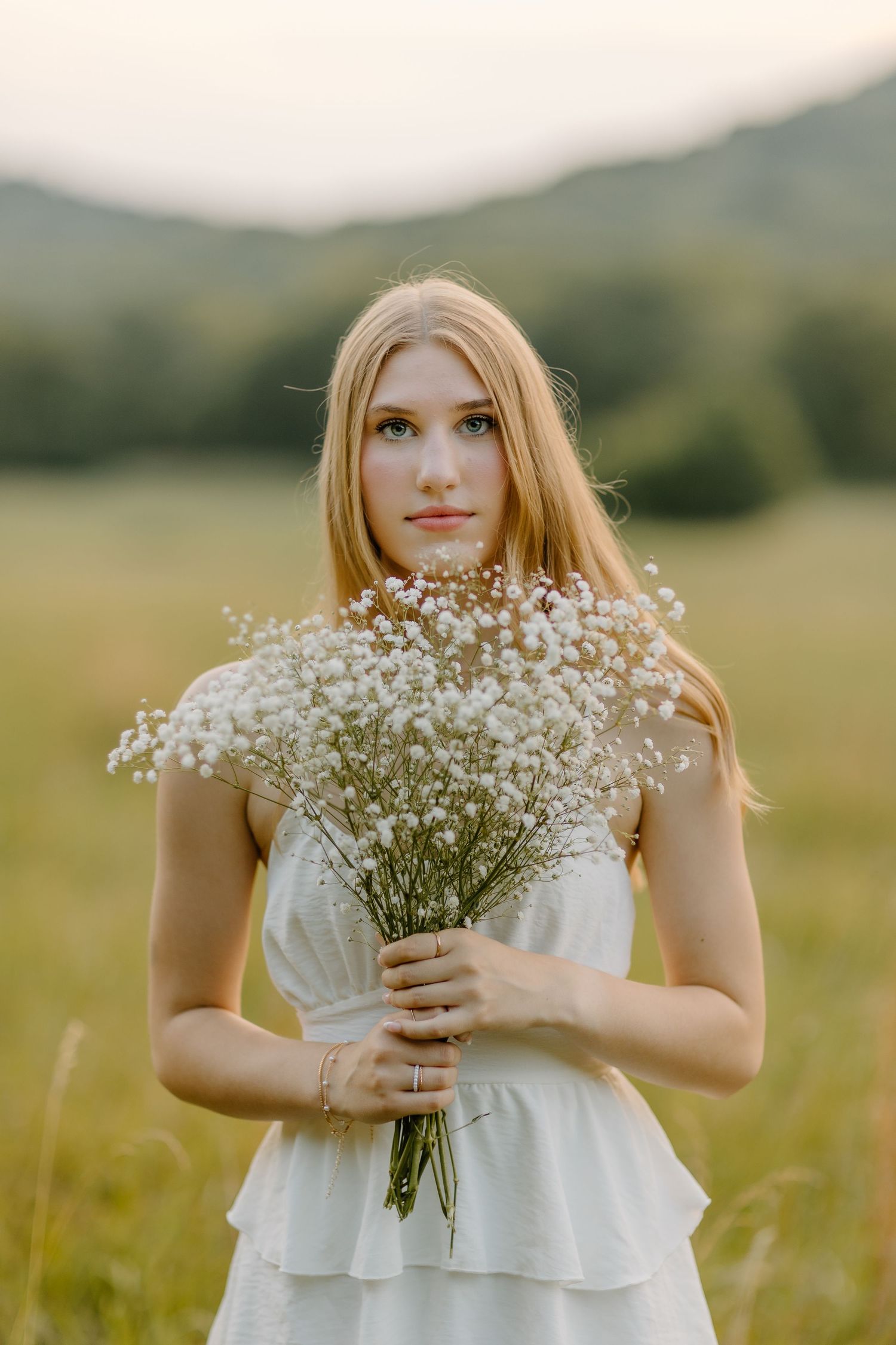 A delicate bouquet of baby's breath flowers held in front of a sunny meadow.