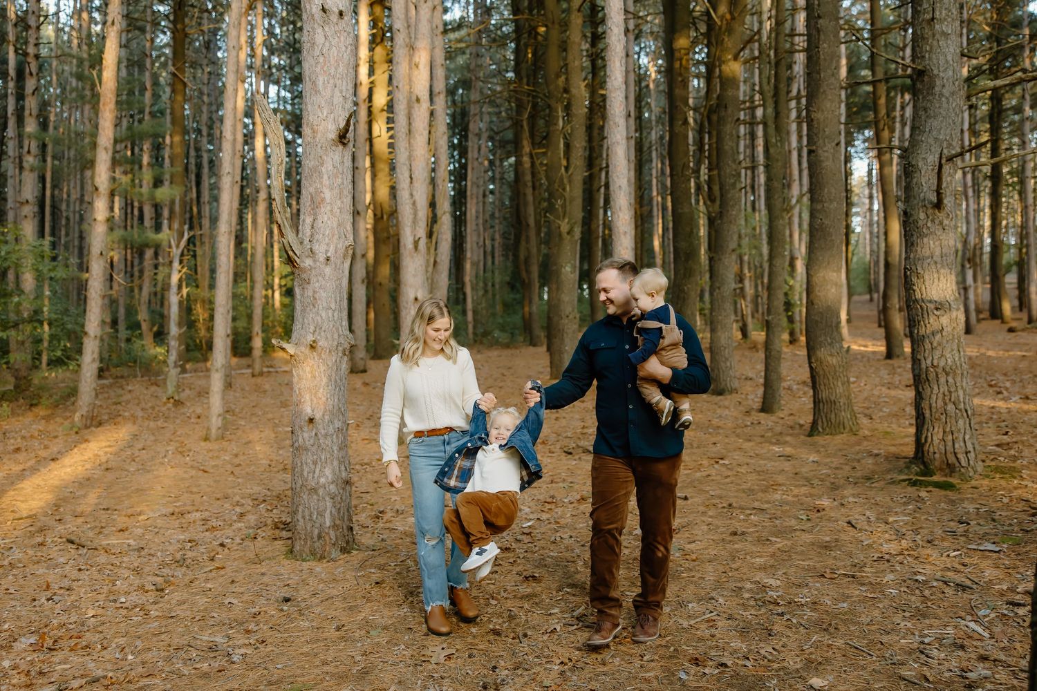 A family walks together through a pine forest on an autumn day.