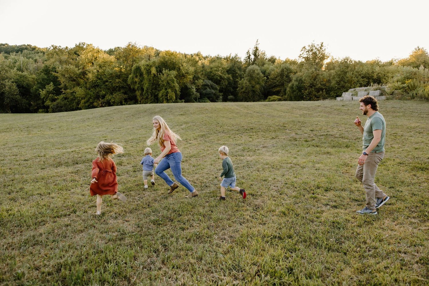 Group enjoying outdoor activities on a grassy hillside in late afternoon light.