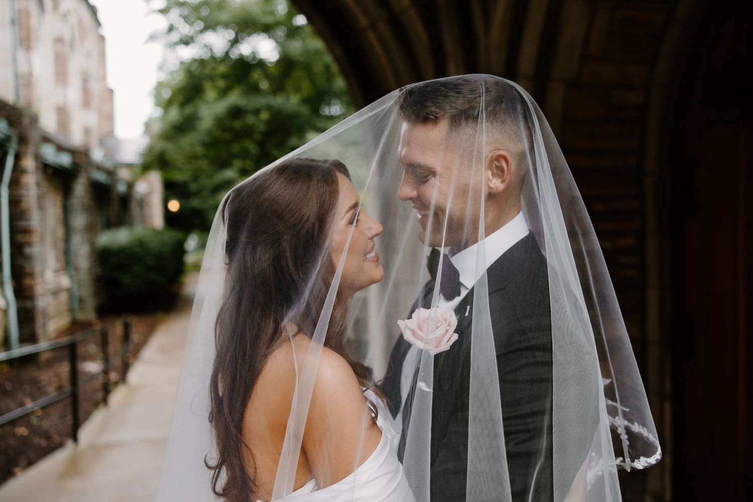 Romantic wedding portraits with flowing veil against architectural backdrop.