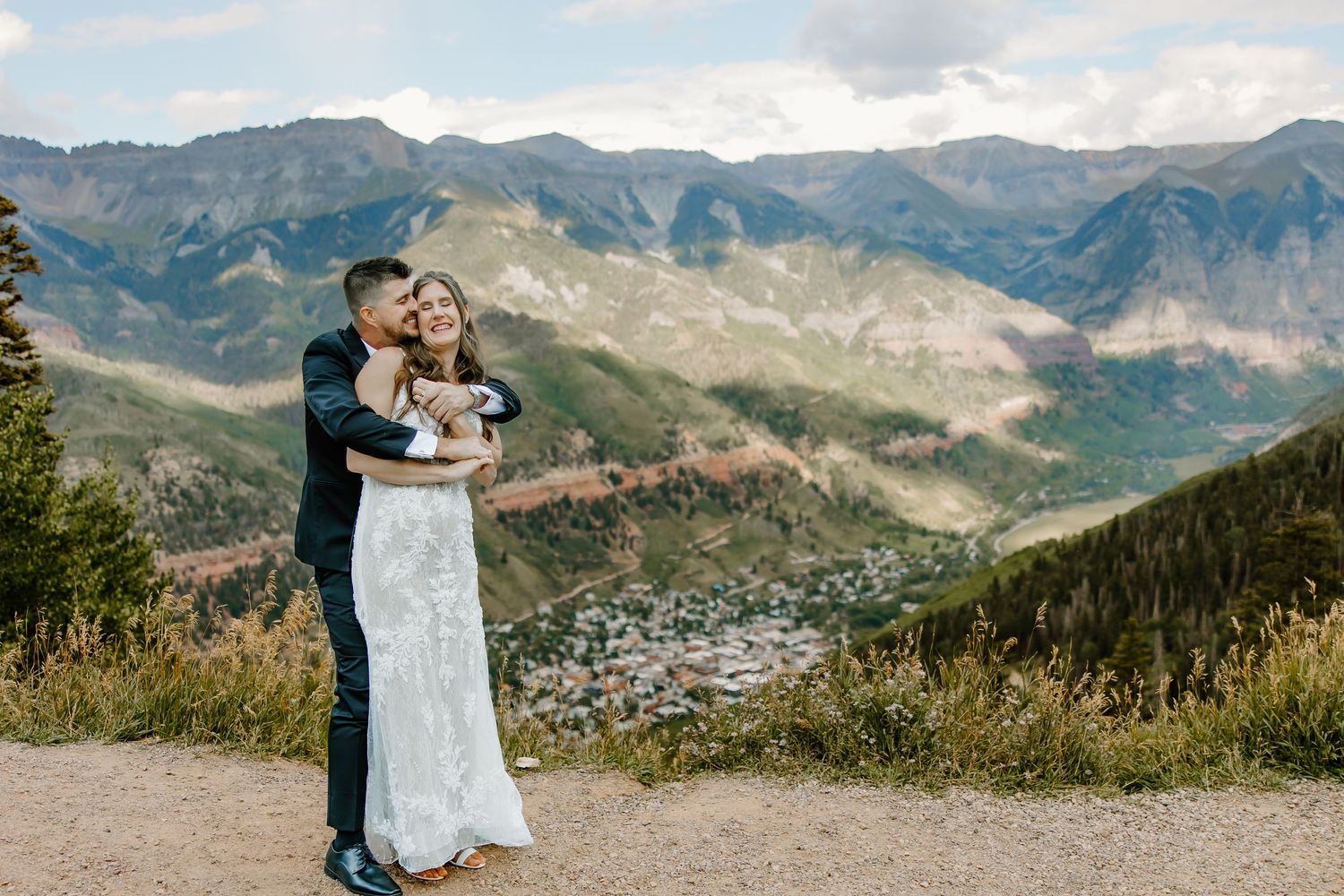 A couple shares an intimate moment against a backdrop of majestic mountain peaks during their wedding photo session.