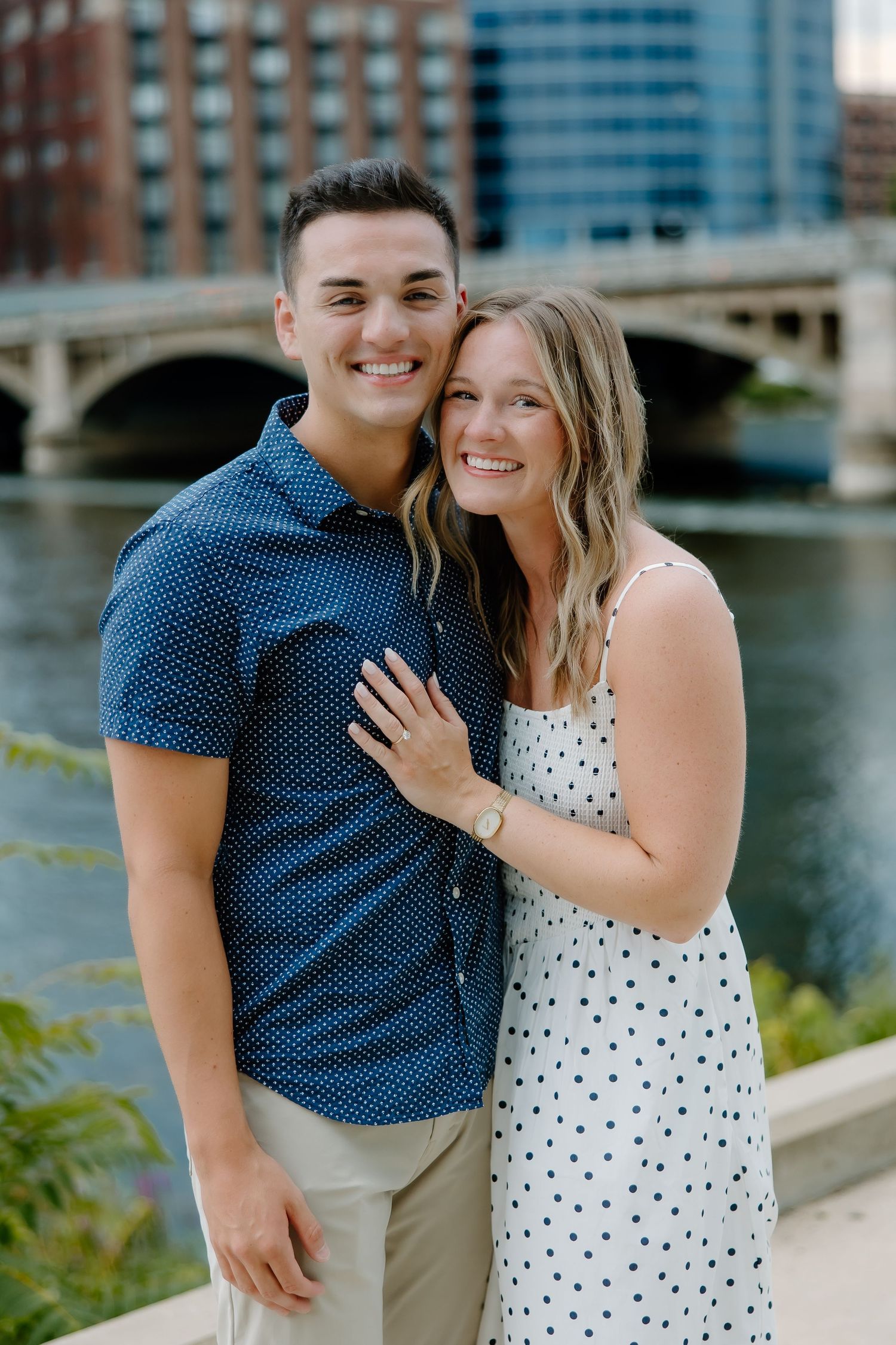 Happy couple in coordinating blue and white polka dot outfits embrace by the water.