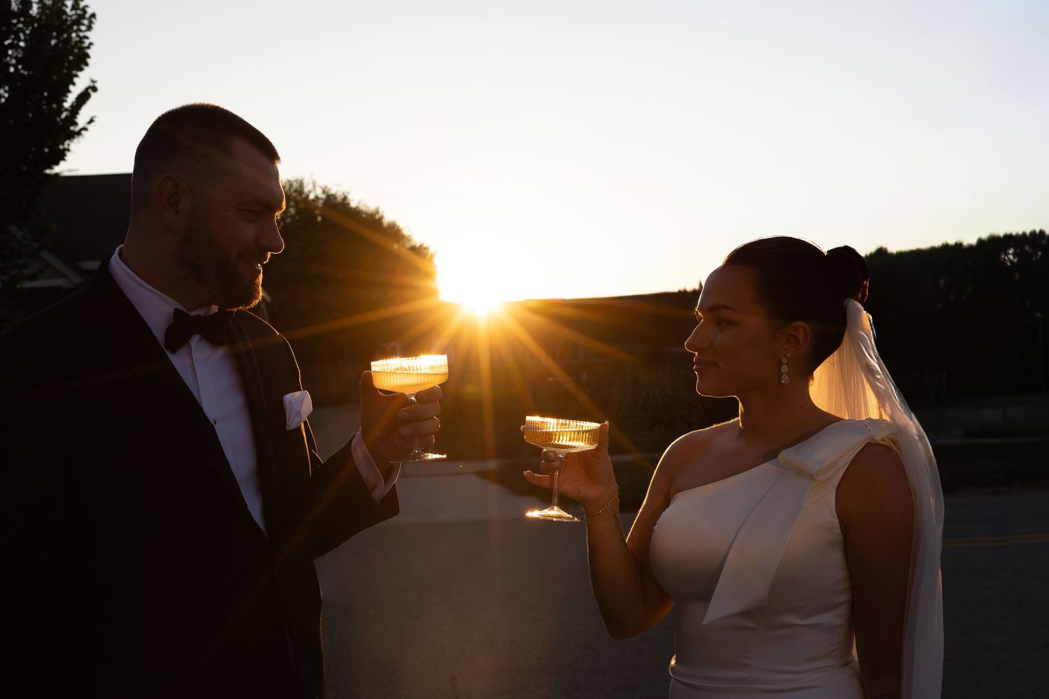 Romantic silhouettes of wedding couple embracing at sunset with golden light streaming through.